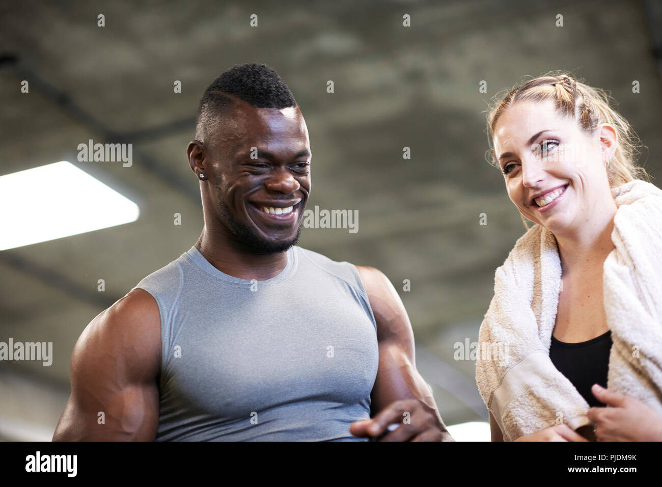 Formateur et cliente de rire dans une salle de sport Banque D'Images