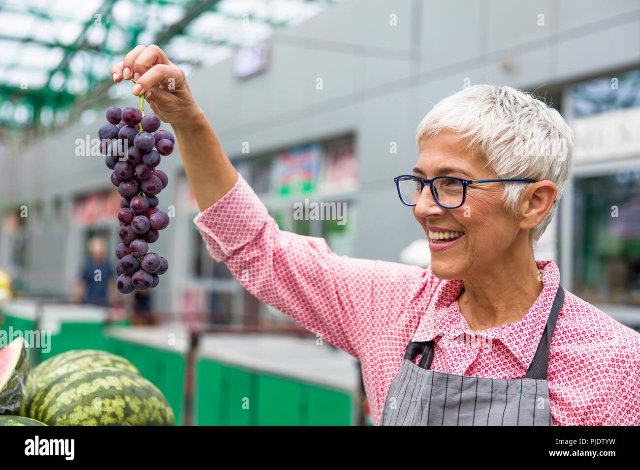 Portrait of senior woman vend des raisins sur market Banque D'Images