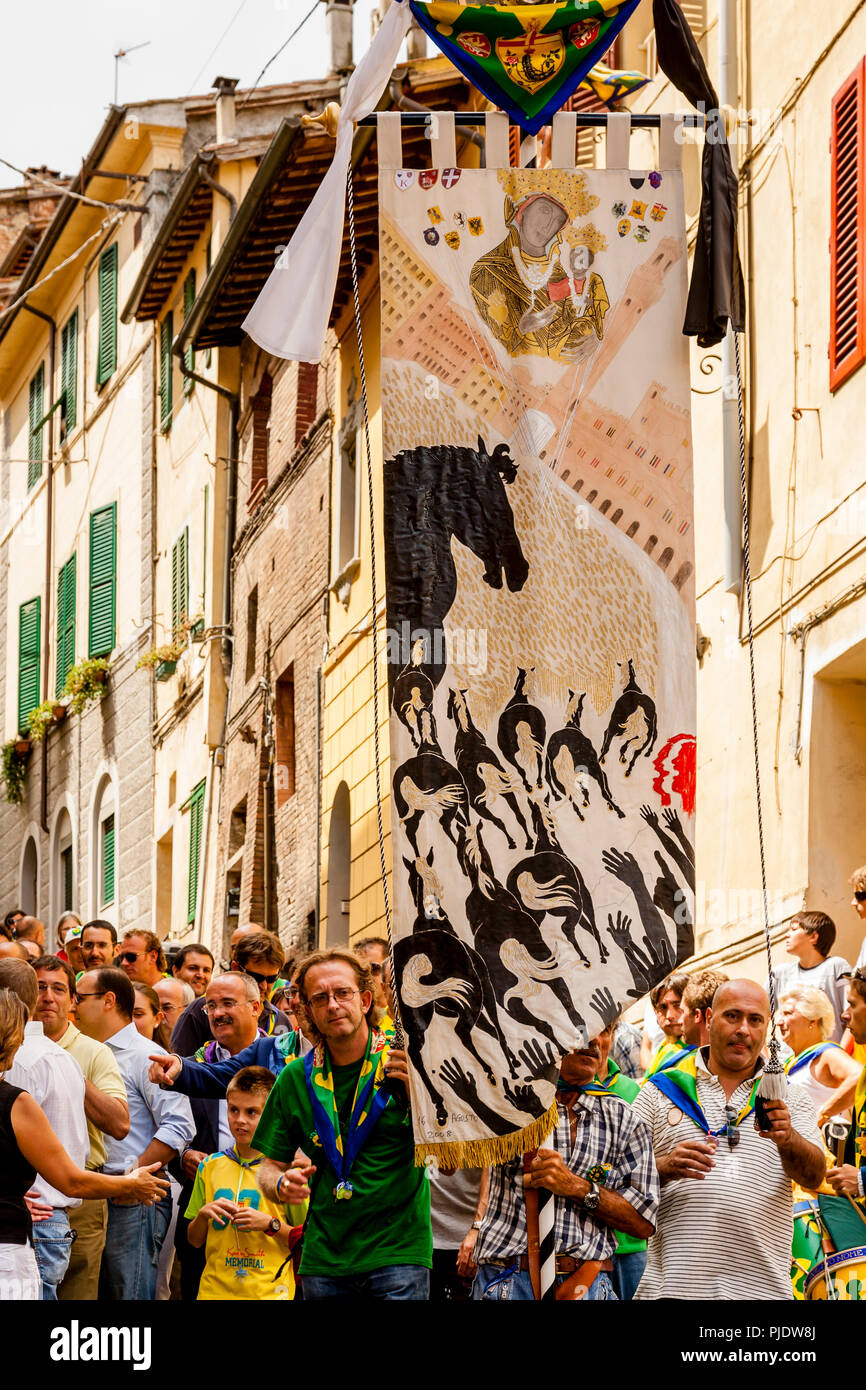 Membres de l'Équipe gagnante Bruco (Caterpillar) Contrada Parade leur prix d'une bannière de soie dans les rues de Sienne, Palio di Siena, Sienne, Italie Banque D'Images