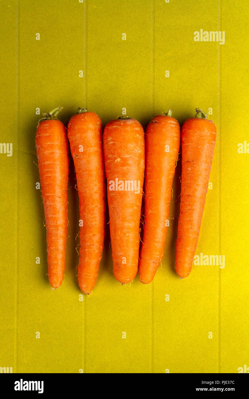 Des carottes crues sur une table en bois jaune Banque D'Images
