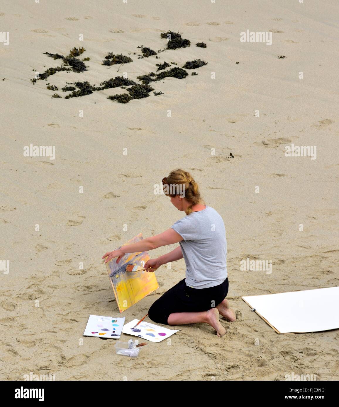 Une femme peinture sur une plage, l'anse de Sennen, Cornwall, Angleterre, Royaume-Uni Banque D'Images