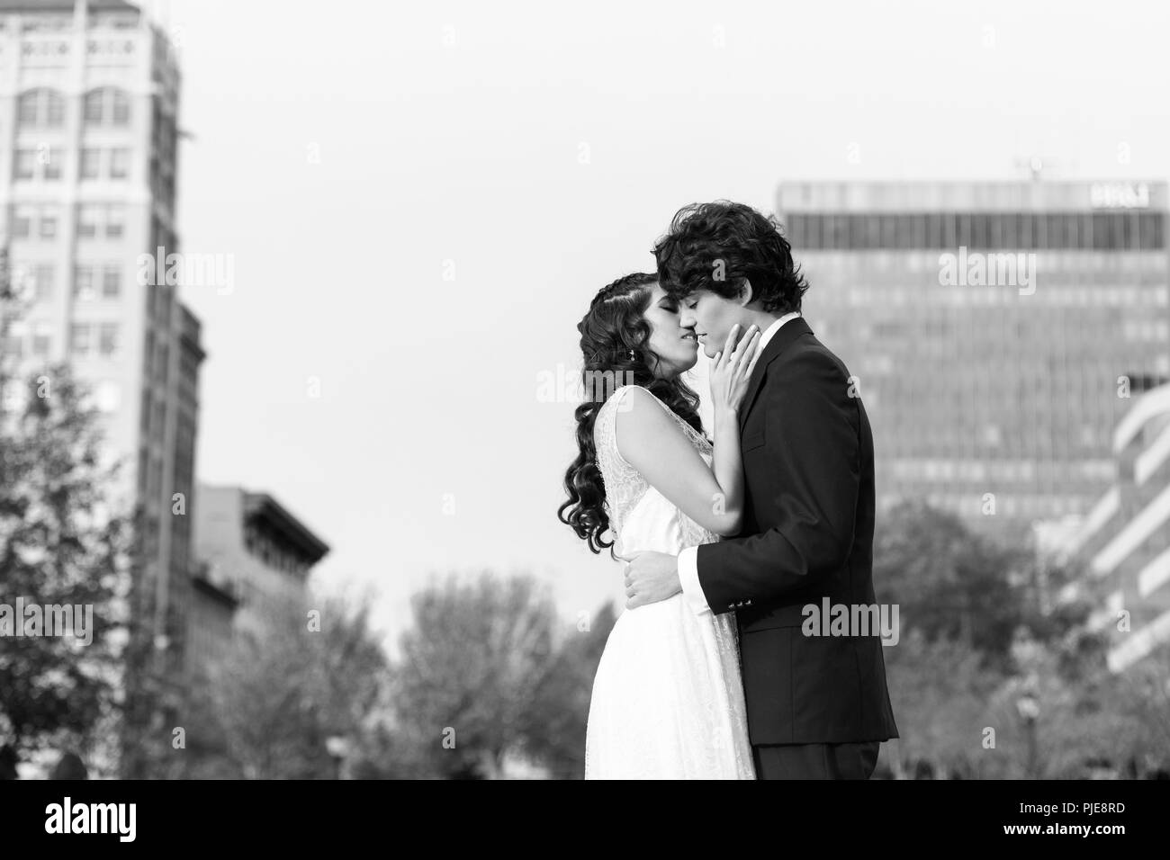 Tourné en noir et blanc du jeune couple s'embrasser tendrement contre un paysage urbain Banque D'Images