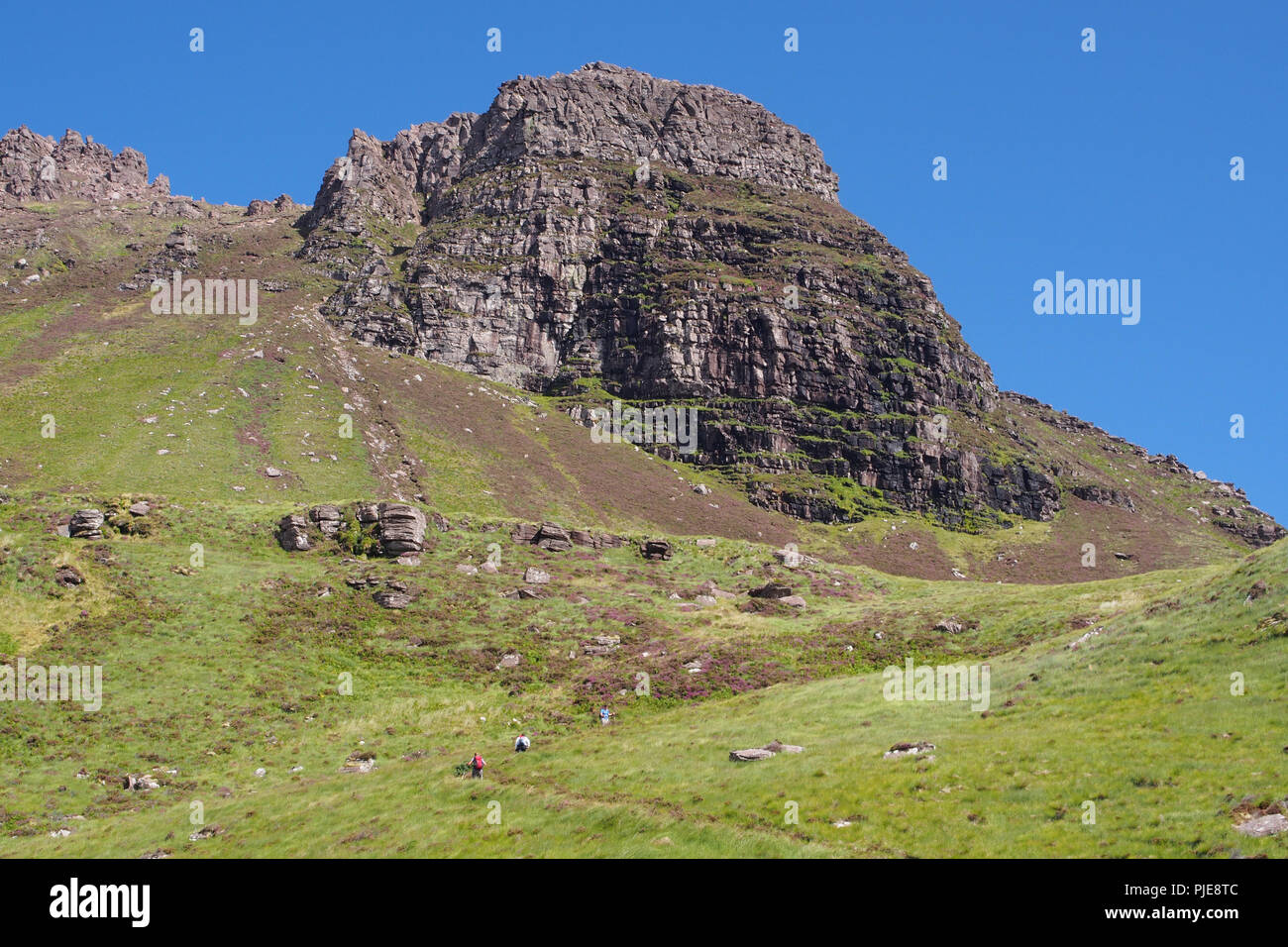 Vue à la Stac Pollaidh, jusqu'à l'Écosse, du côté sud, parking, chemin avec trois marcheurs de colline en remontant la piste de montagne aux roches Banque D'Images
