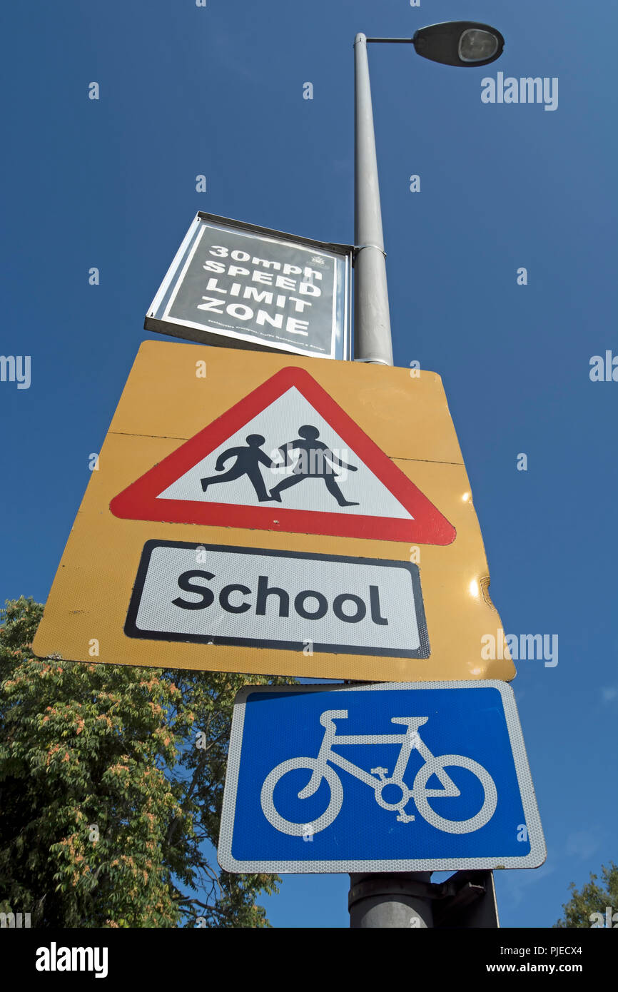 La signalisation routière indiquant une école avec des enfants qui traversent la route d'une limite de vitesse de 30 mi/h, et une randonnée à vélo, à Surbiton, Surrey, Angleterre Banque D'Images