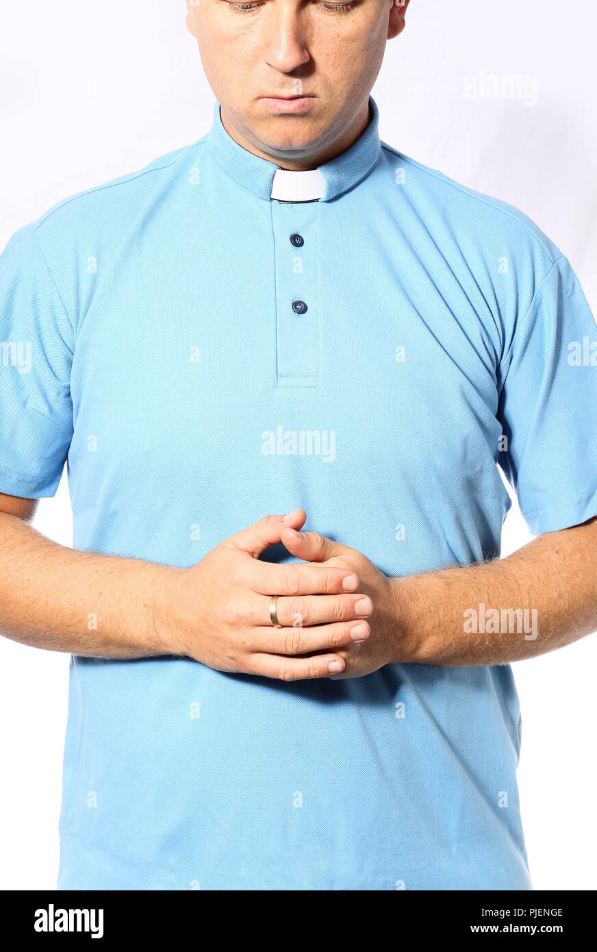 Jeune prêtre prie dans une chemise bleue Banque D'Images