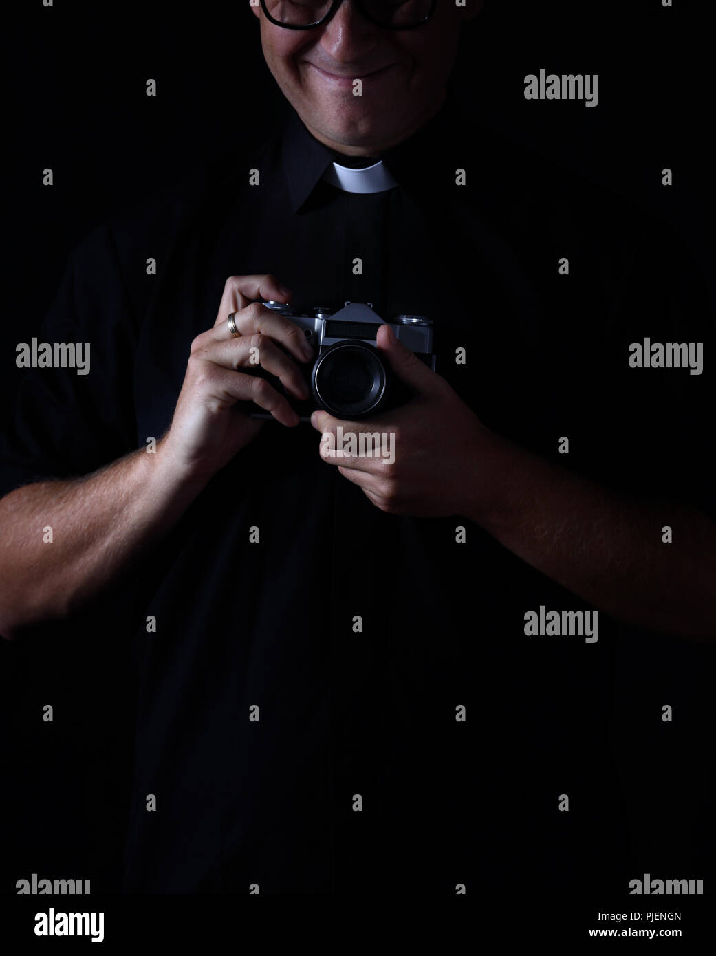 Prêtre souriant avec l'appareil photo Banque D'Images