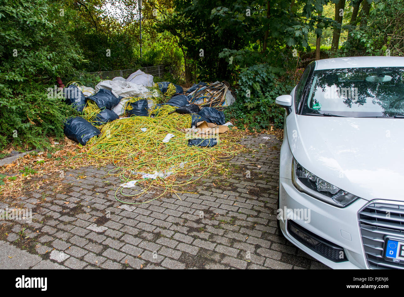 Dépotoir sauvage sur un terrain de stationnement public, l'élimination illégale de déchets de construction, déchets de câbles, à grande échelle, la poubelle a été déposée plus tard f Banque D'Images