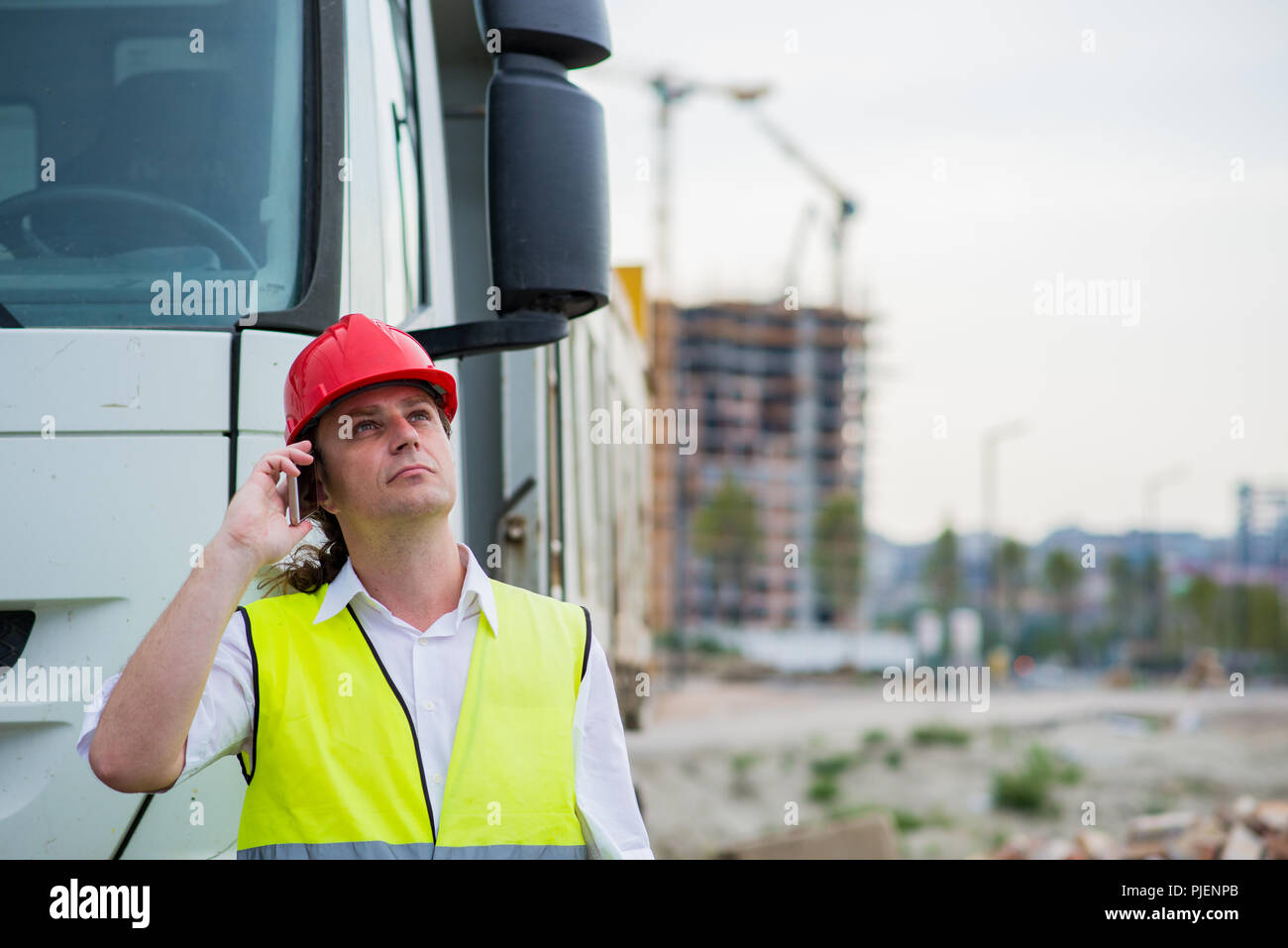 Chauffeur de camion à parler sur son téléphone portable sur un site de construction Banque D'Images