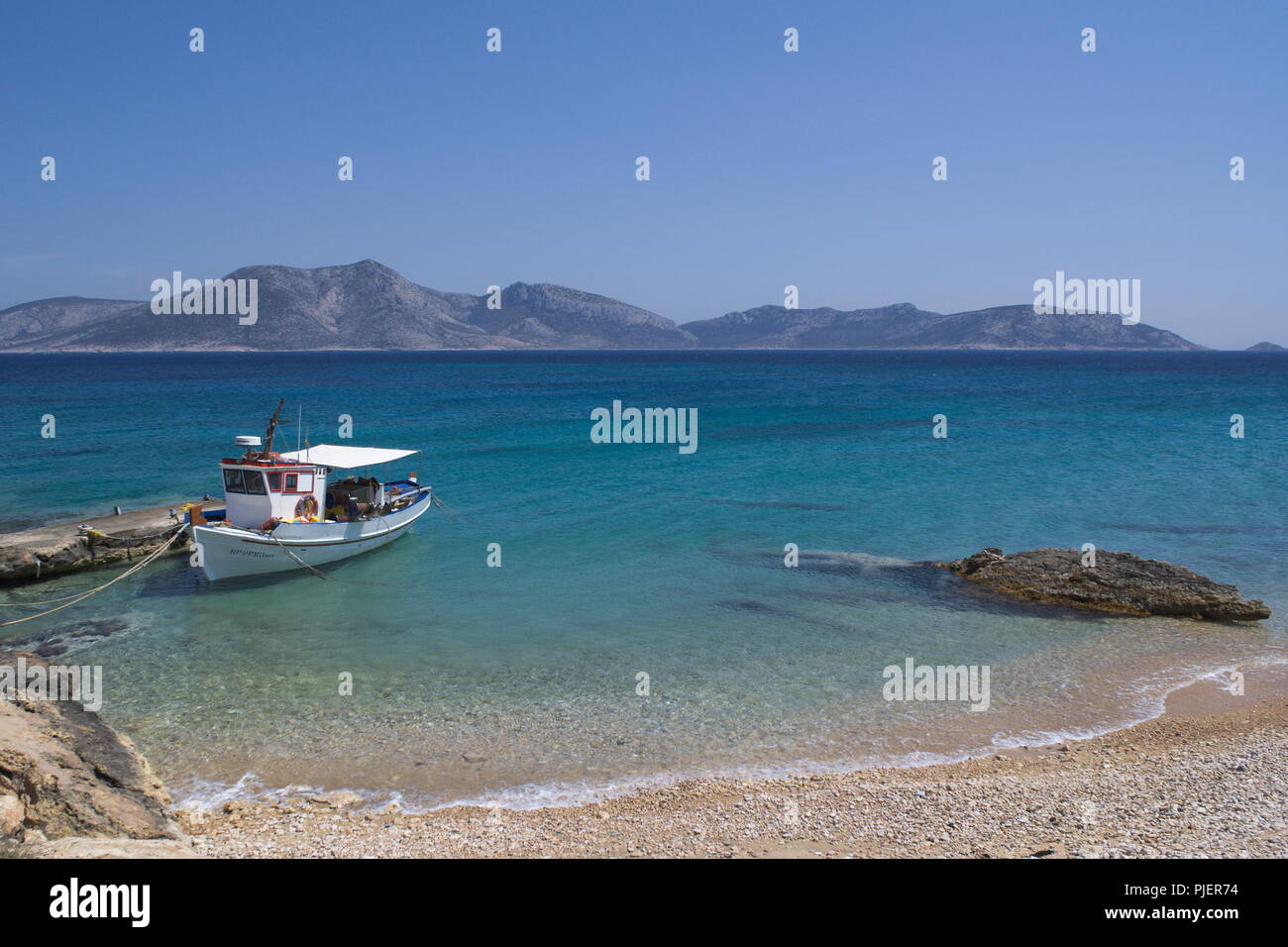 Grèce, la belle île de Koufonissi. Un petit bateau de pêche est amarré à une petite jetée sur une plage. Au loin se trouve l'île de Keros. Banque D'Images