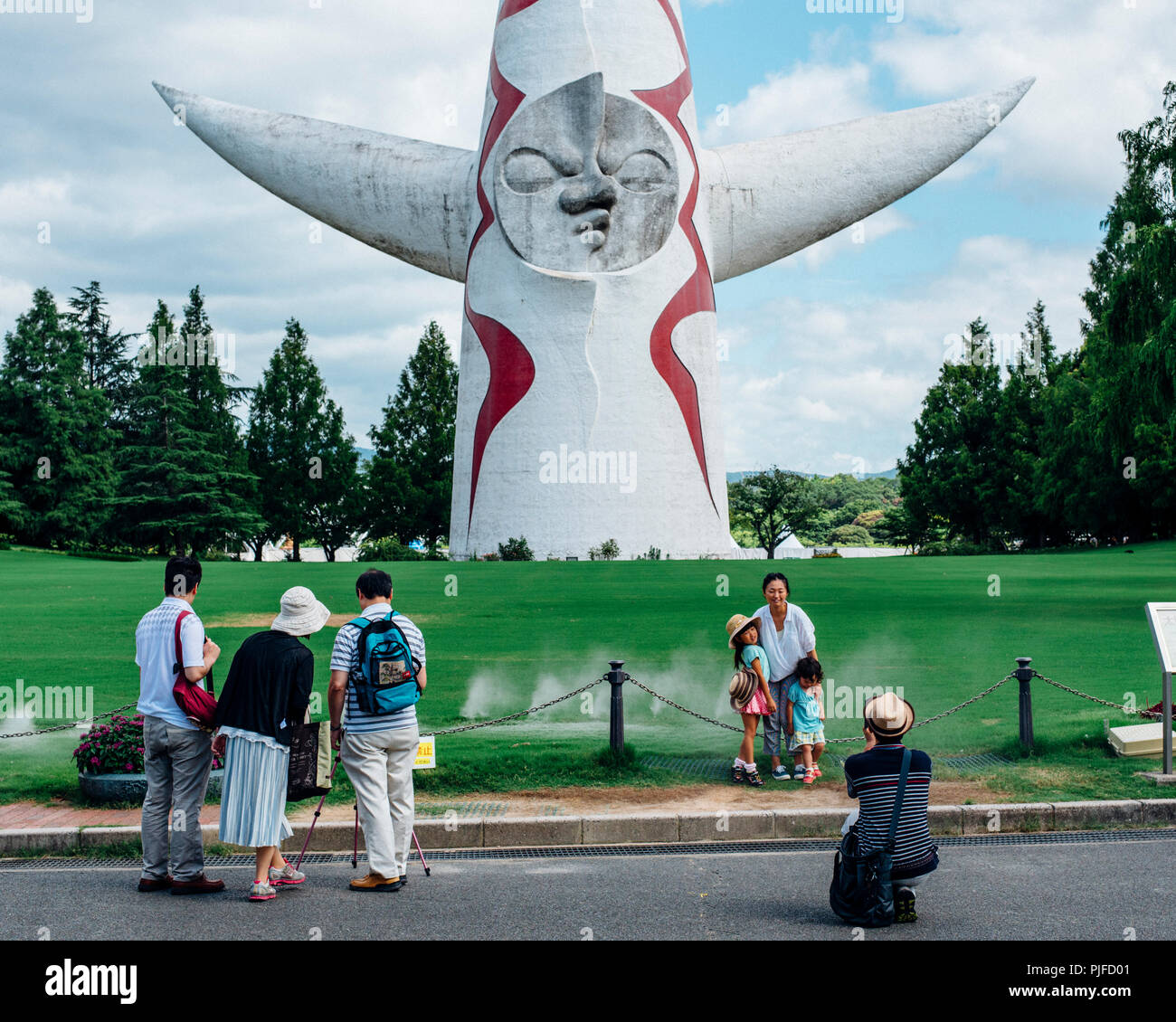 Famille posant devant la tour de Taro Okamoto le soleil statue au Parc Exposition Banpaku. Osaka, Japon Banque D'Images