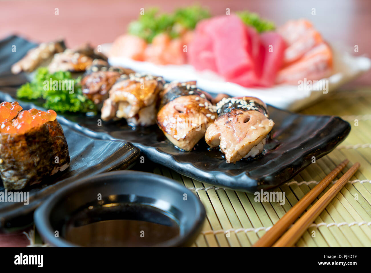 Sushi avec des baguettes et de la sauce de soja. Sushi roll Japanese food in restaurant. Jeu de Sushi de foie gras avec du saumon, thon, oeufs de poisson volant et le caviar closeup Banque D'Images