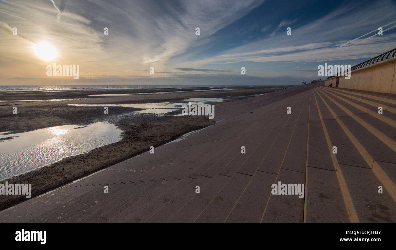 Le soleil se couche sur la mer d'Irlande, de l'éclairage les flaques sur le sable de la plage de Blackpool, vu depuis les étapes de la promenade digue. Banque D'Images