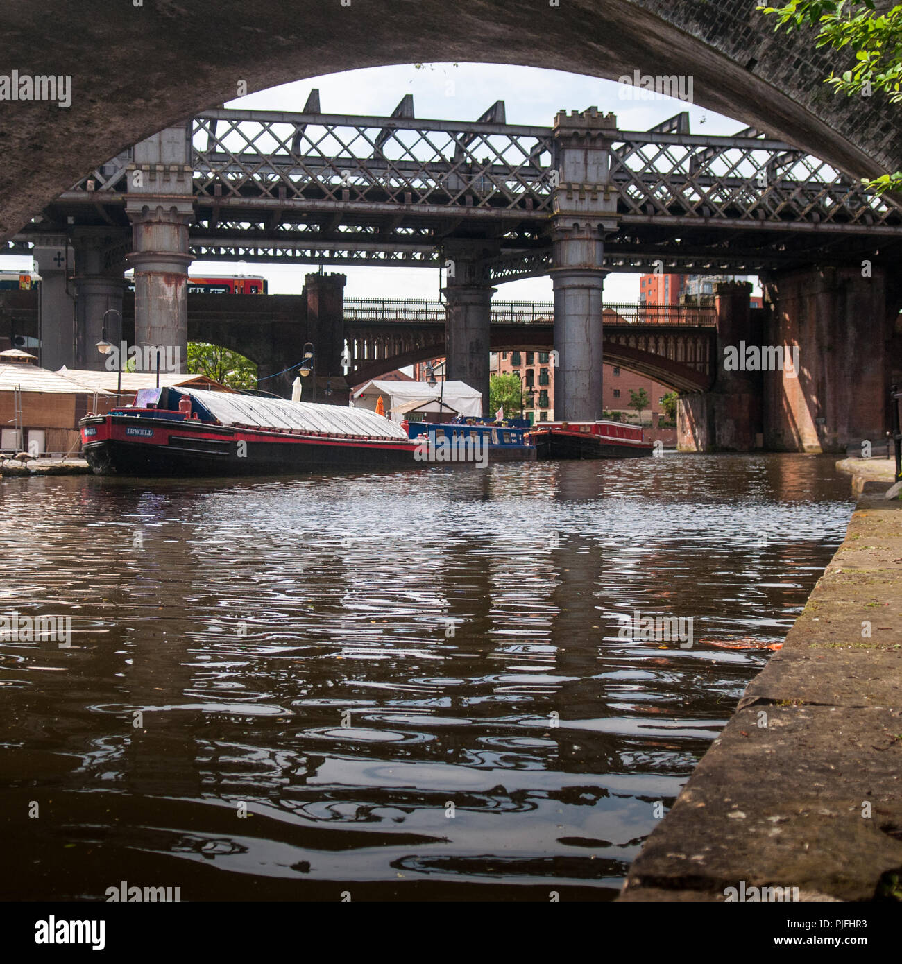 Manchester, Angleterre, Royaume-Uni - Mai 21, 2011 : un train de voyageurs Trains traverse le Castlefield bassin, sur le Canal de Bridgewater à Manchester. Banque D'Images