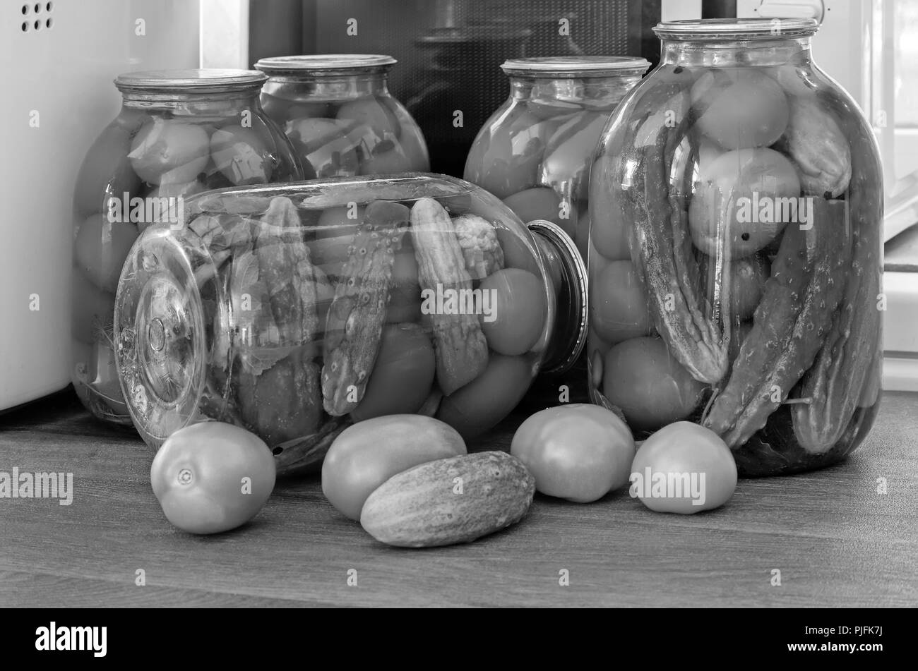 Accueil préservation : grands pots en verre rouge avec des tomates mûres et concombres, scellée. metallid Image noir et blanc. Banque D'Images