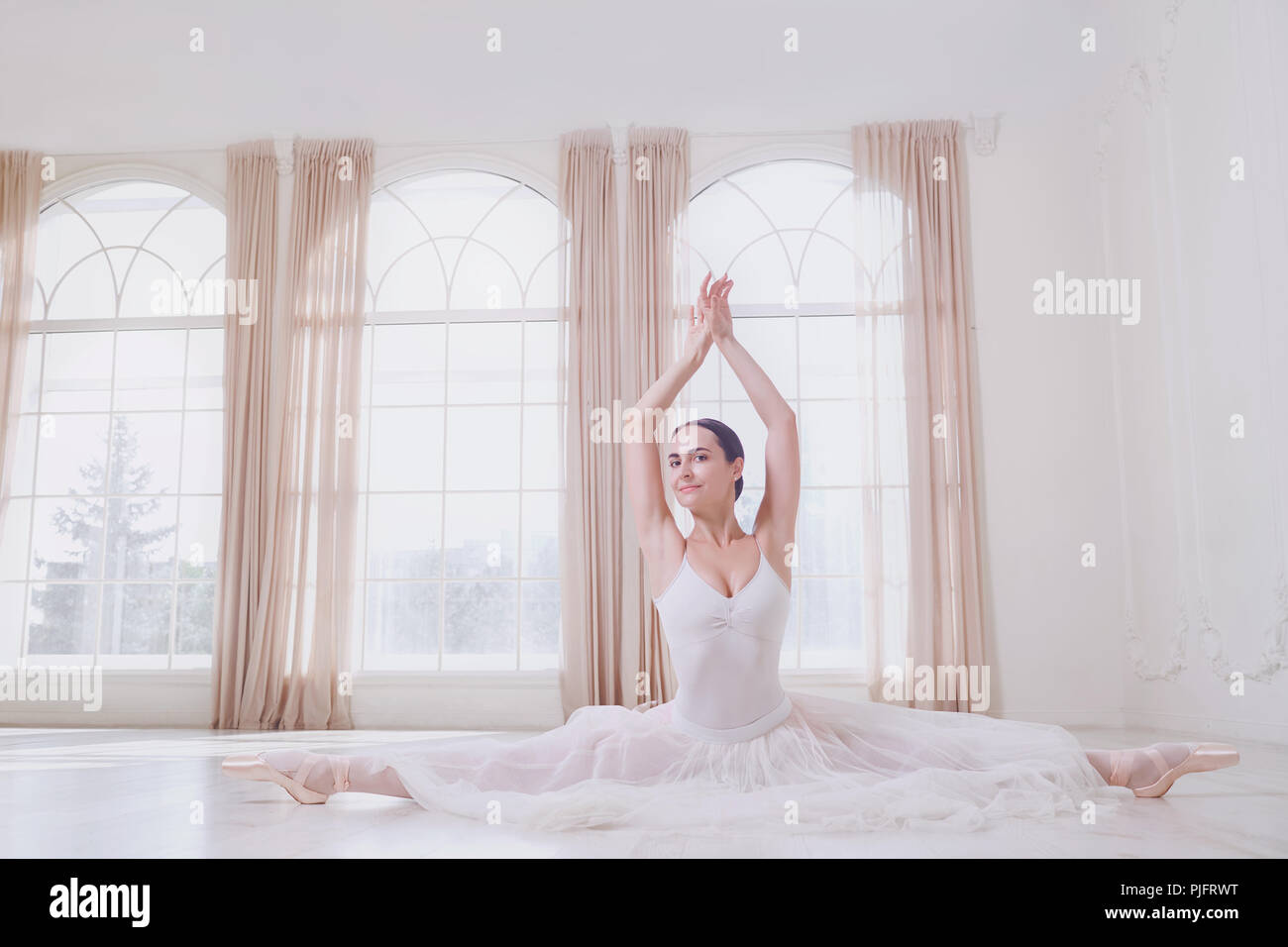 Une ballerine sur une ficelle dans des vêtements blancs dans un livre blanc studio. Banque D'Images
