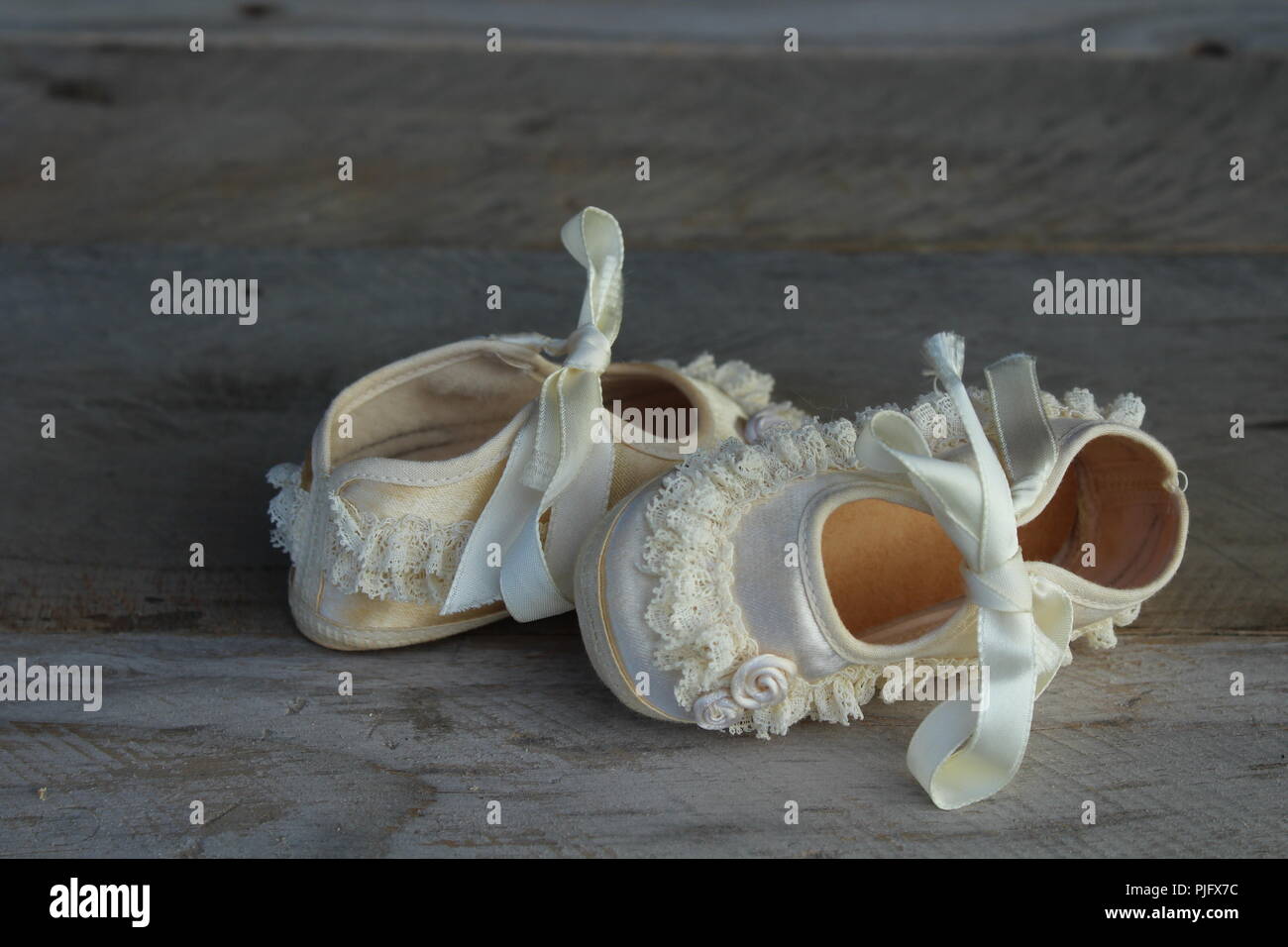 Vintage Chaussures de bébé avec des volants et des fleurs sur un fond de bois naturel Banque D'Images