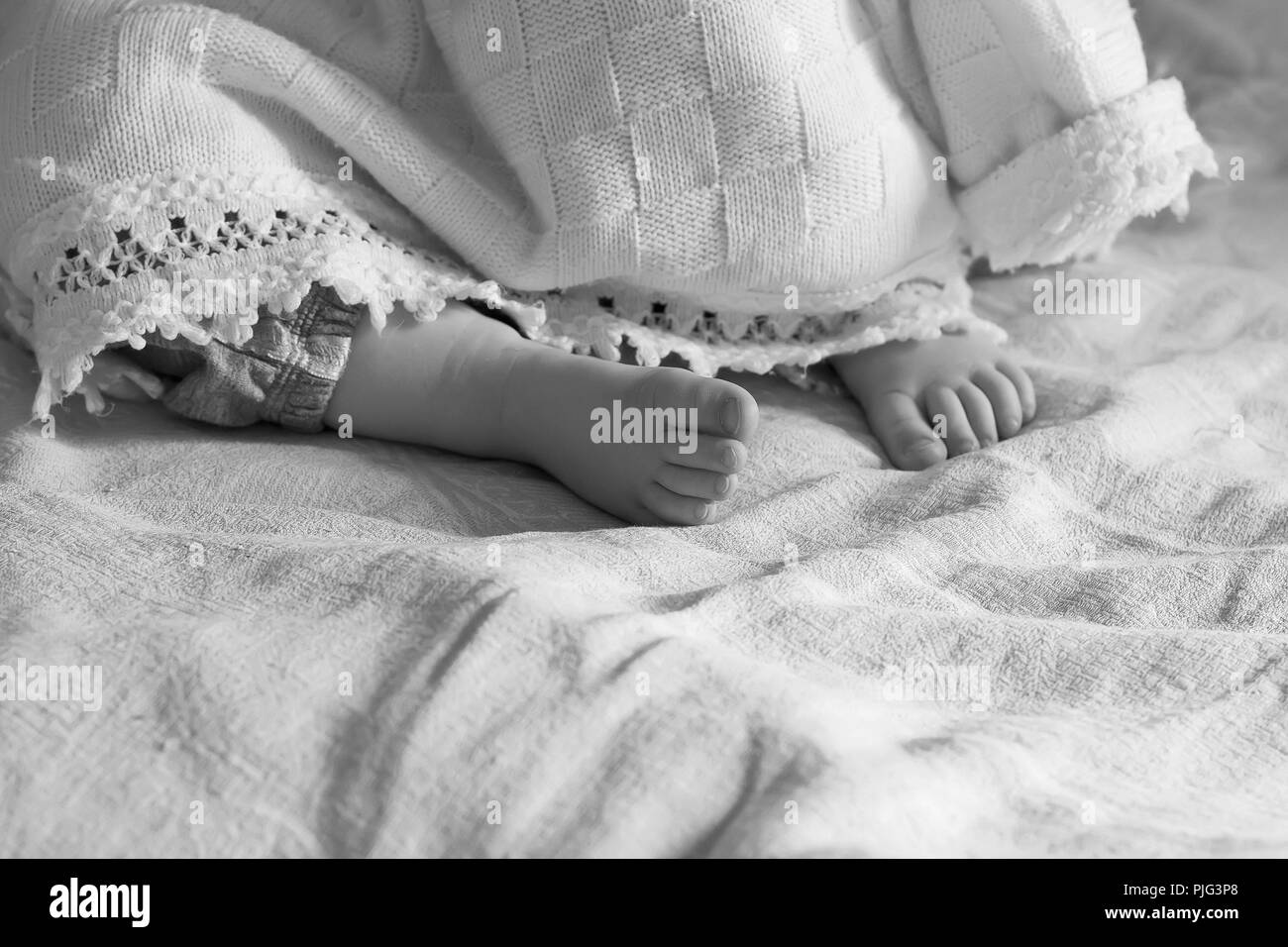 Couchage talon baby girl qui sort de sous la couverture en noir et blanc, selective focus Banque D'Images