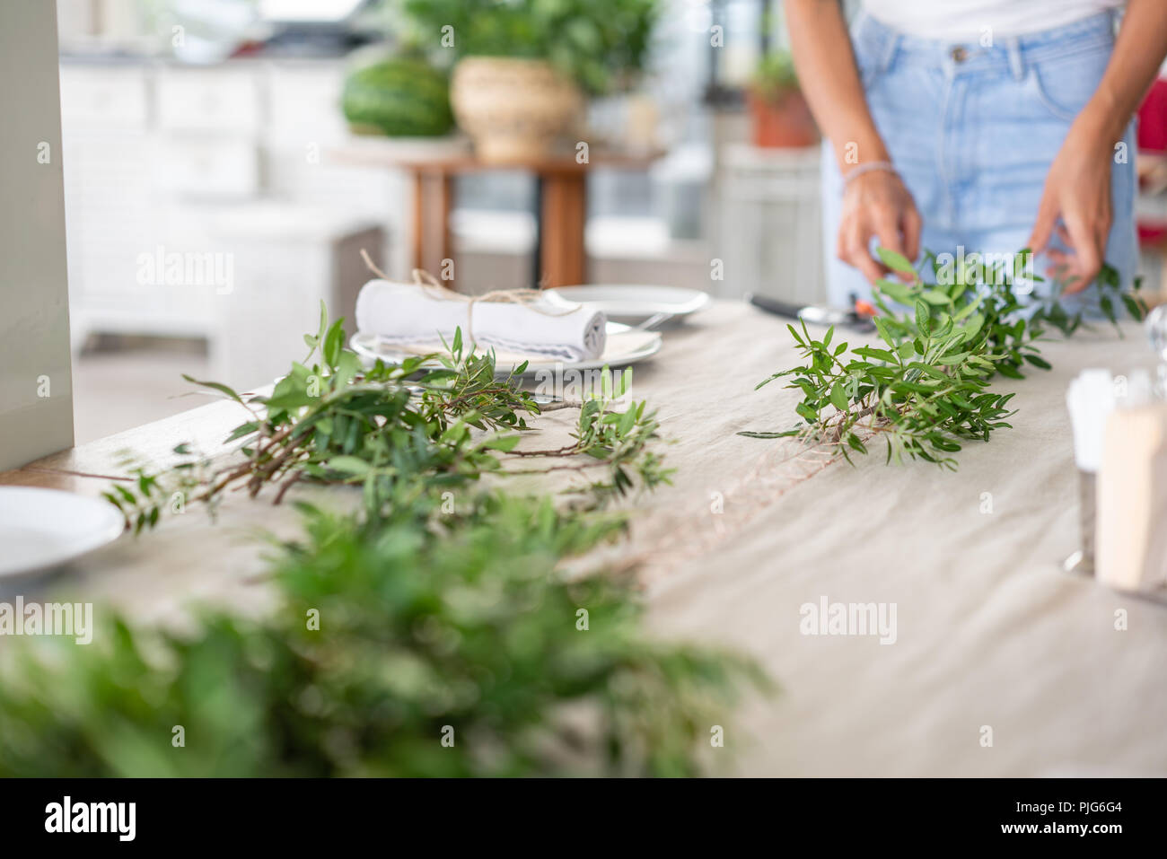 Fleur fleuriste crée une guirlande de verdure, la préparation de la fête de mariage. Banquet ou dîner de gala. Recouverte d'une nappe en lin runner. partie sur terrasse Banque D'Images