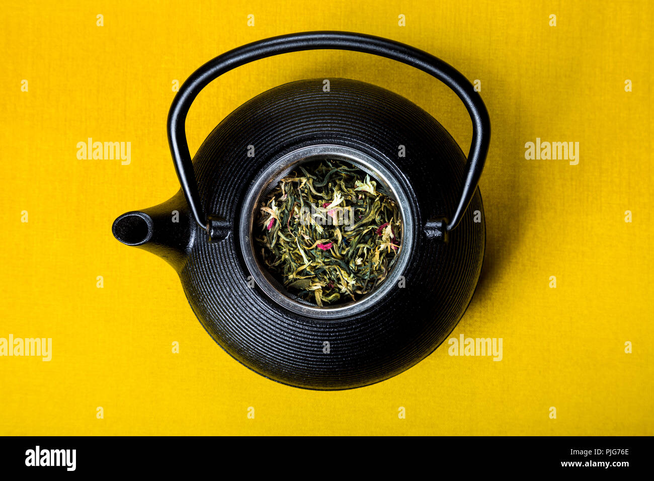 Théière en fonte (tetsubin) avec feuilles en vrac Thé blanc contre fond jaune Banque D'Images