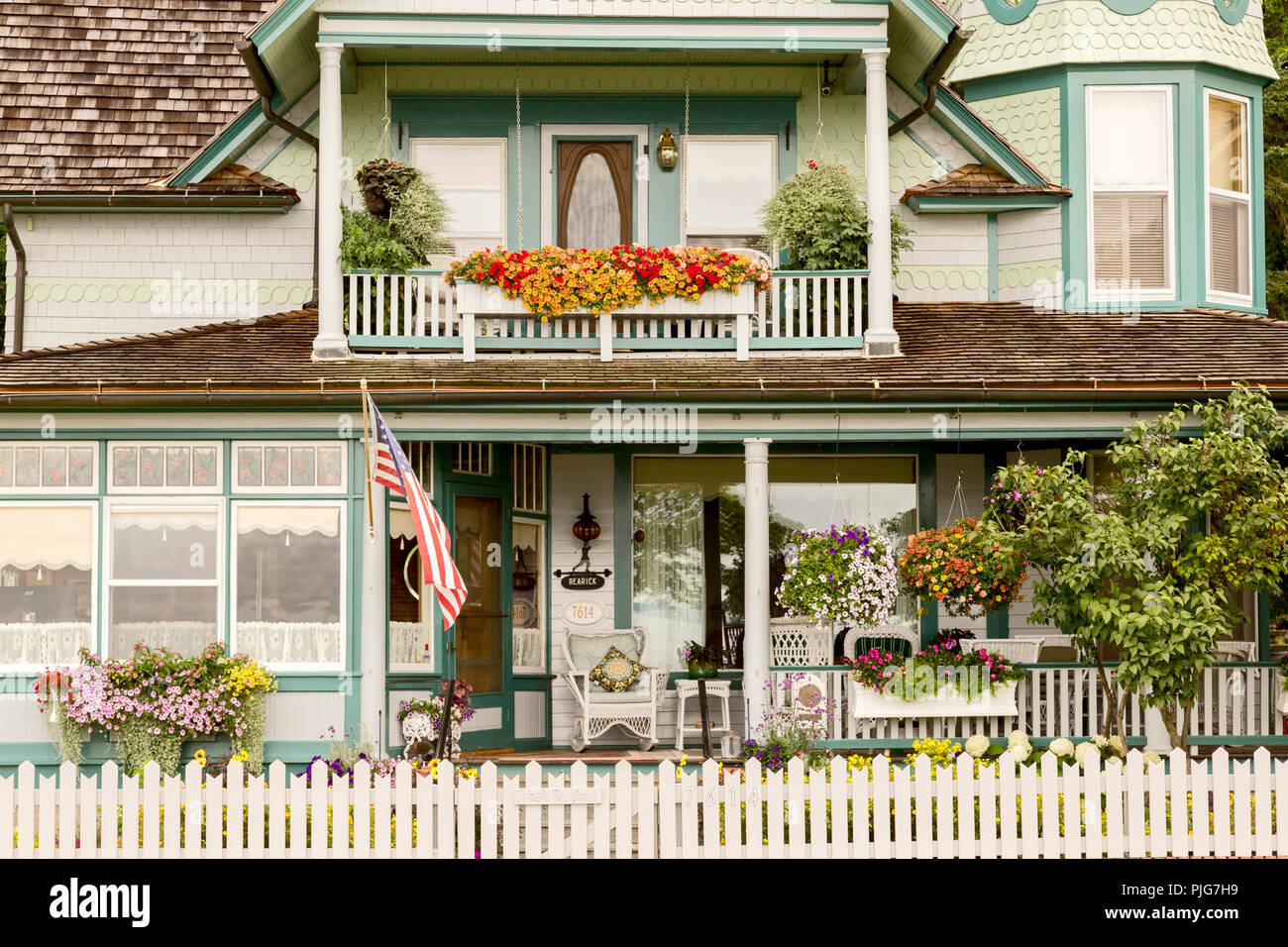 Gros plan d'une belle maison de style Victorien sur l'historique de l'île Mackinac, Michigan, USA. décorées de fleurs et le drapeau américain, Banque D'Images