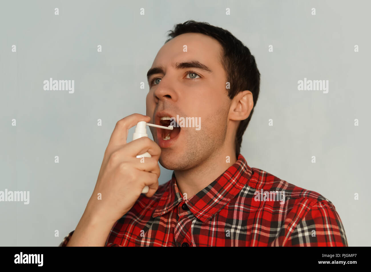 L'homme malade traite la gorge spray spray spray blanc de la médecine. Jeune mec est malade avec un rhume. Traitement de l'enflure des ganglions de la gorge. Un refres Banque D'Images