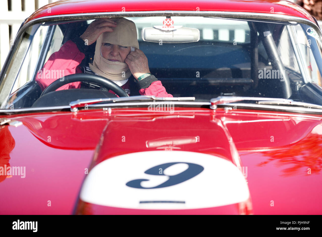 Un pilote sur le Trophée Kinrara ajuste son capot feu avant de pratiquer le premier jour de l'Goodwood Revival au Goodwood Motor Circuit, dans la région de Chichester. Banque D'Images