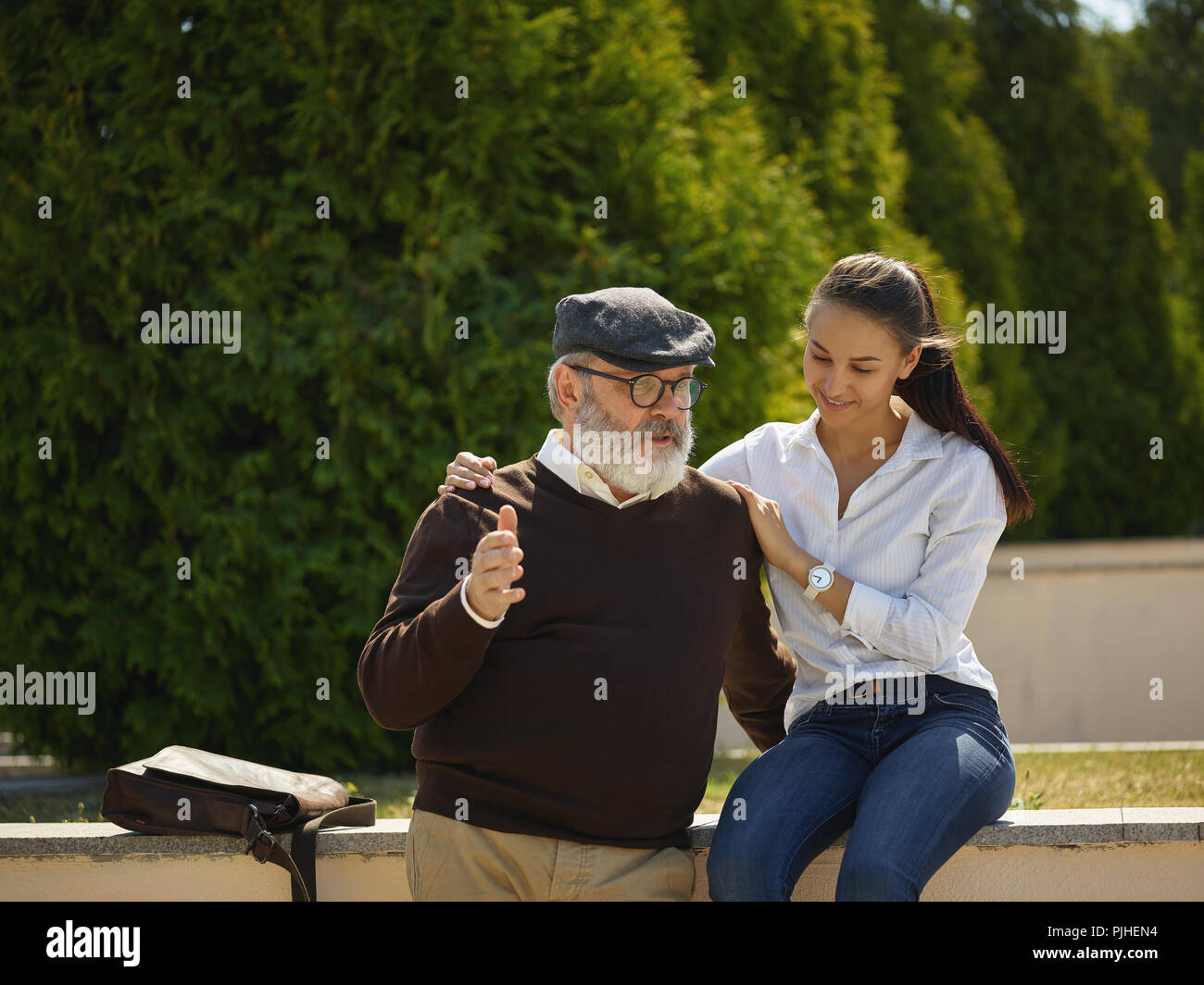 Aider quelqu'un que vous aimez. Portrait of young smiling girl embracing grand-père contre city park. communauté et de vie de la famille concept Banque D'Images