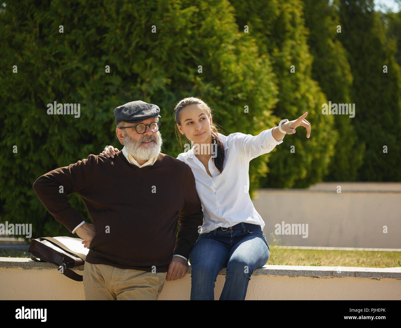 Aider quelqu'un que vous aimez. Portrait of young smiling girl embracing grand-père contre city park. communauté et de vie de la famille concept Banque D'Images