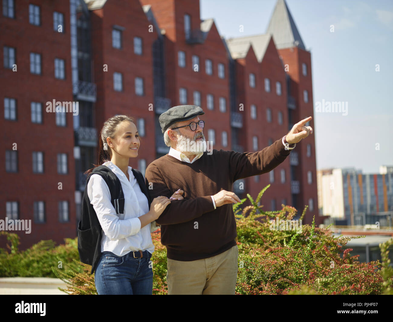 Aider quelqu'un que vous aimez. Portrait of young smiling girl embracing grand-père contre city park. communauté et de vie de la famille concept Banque D'Images