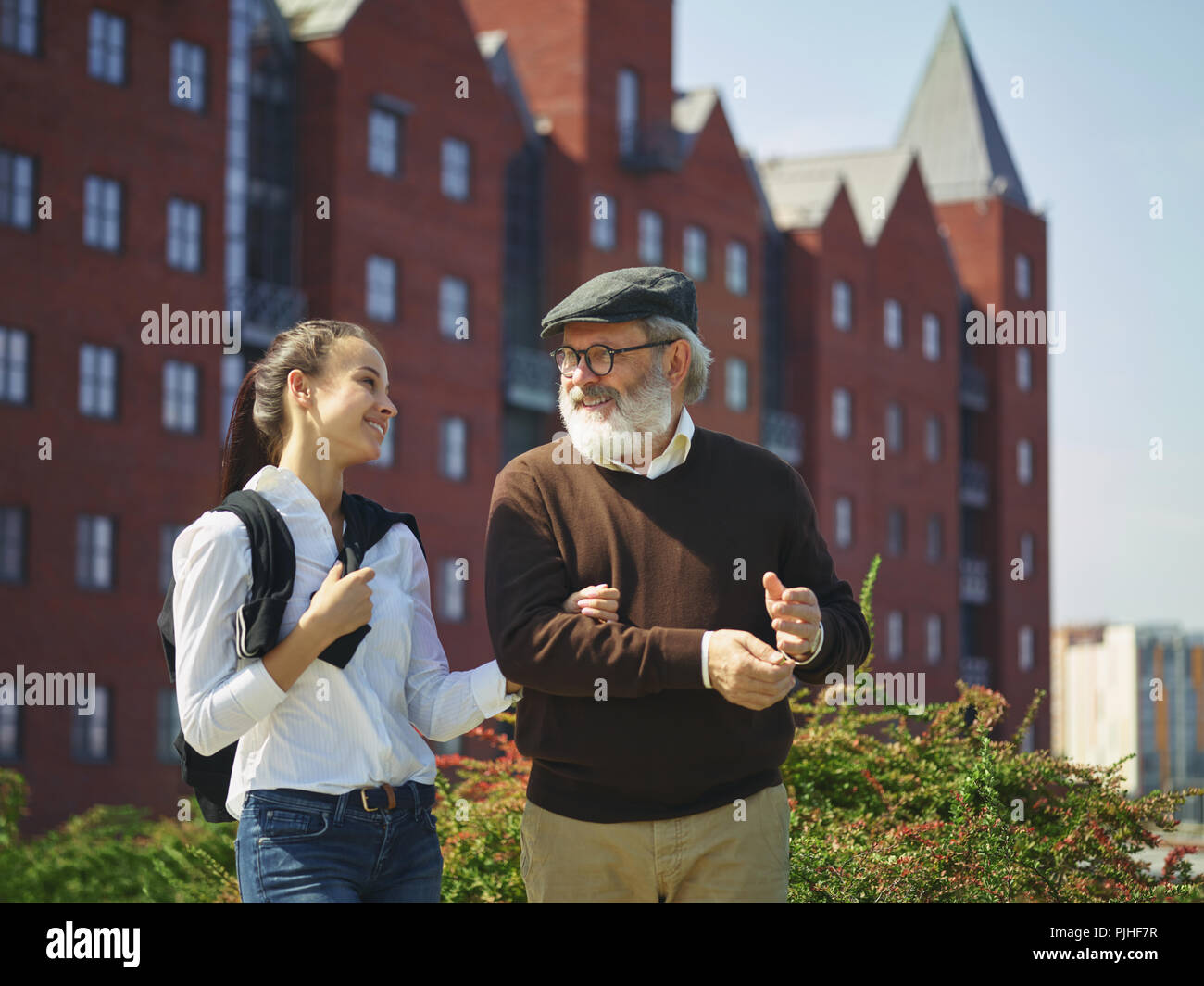 Aider quelqu'un que vous aimez. Portrait of young smiling girl embracing grand-père contre city park. communauté et de vie de la famille concept Banque D'Images