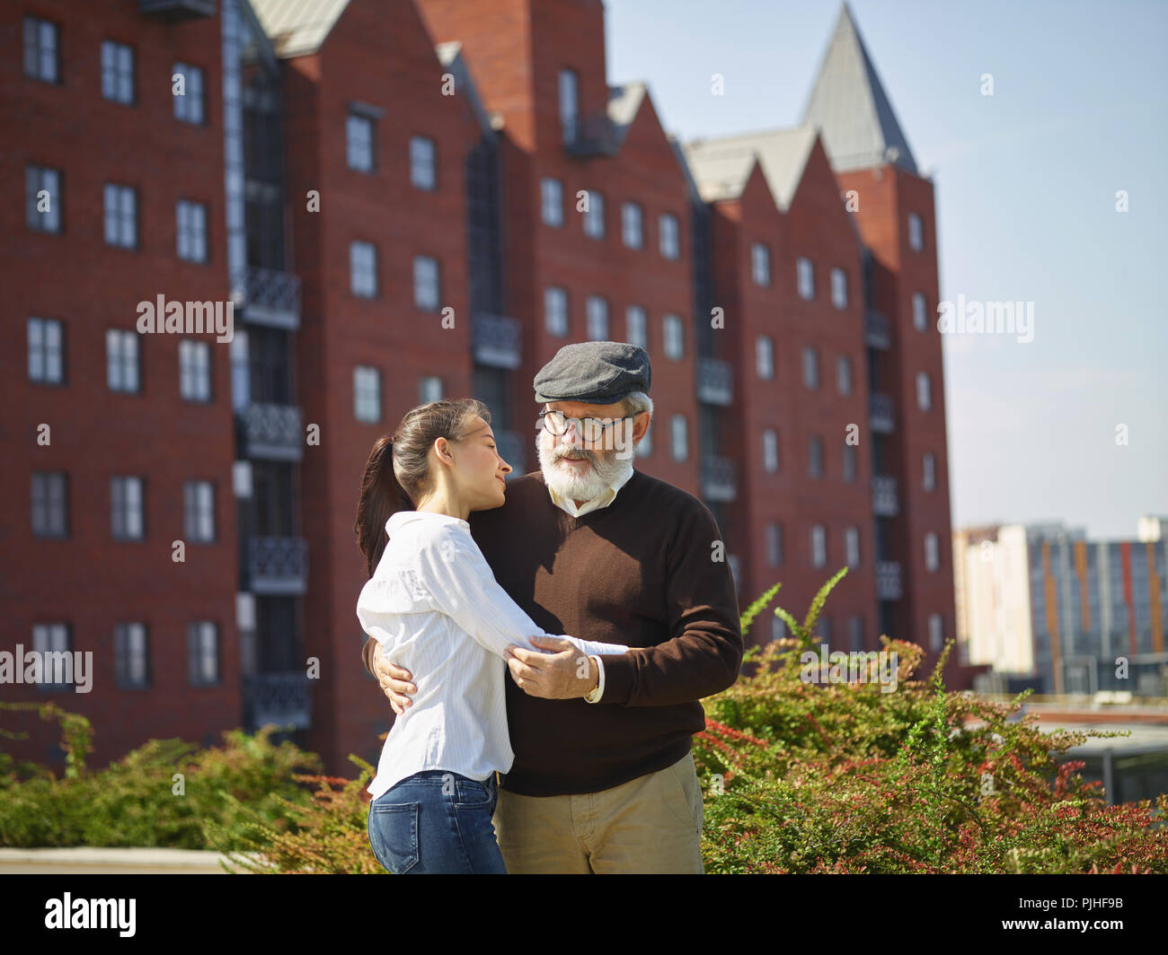 Aider quelqu'un que vous aimez. Portrait of young smiling girl embracing grand-père contre city park. communauté et de vie de la famille concept Banque D'Images