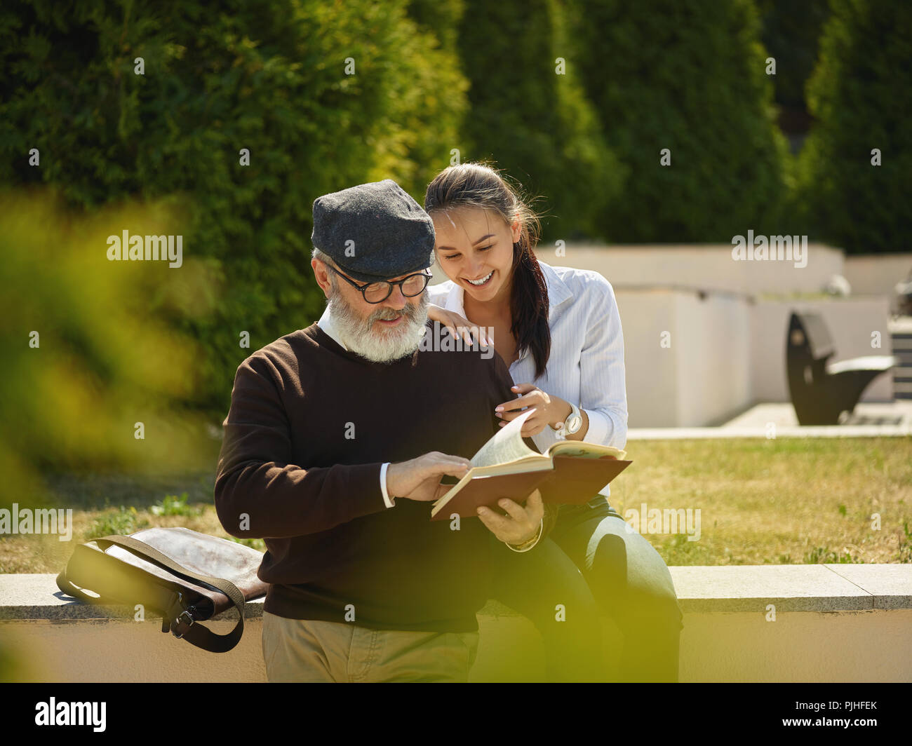 Aider quelqu'un que vous aimez. Portrait of young smiling girl embracing grand-père avec réserve contre city park. communauté et de vie de la famille concept Banque D'Images