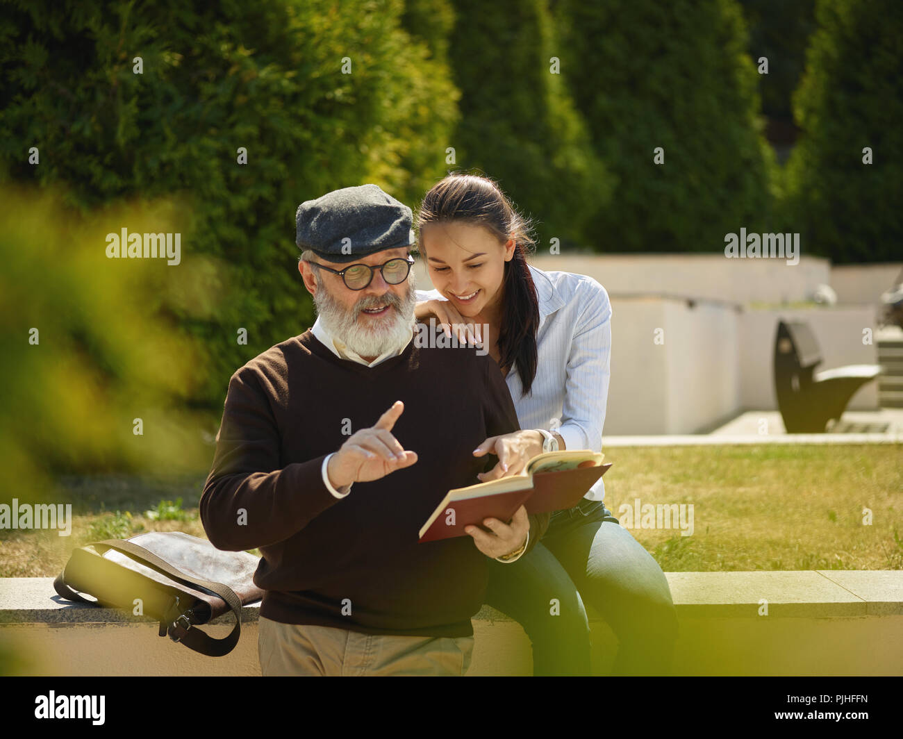 Aider quelqu'un que vous aimez. Portrait of young smiling girl embracing grand-père avec réserve contre city park. communauté et de vie de la famille concept Banque D'Images