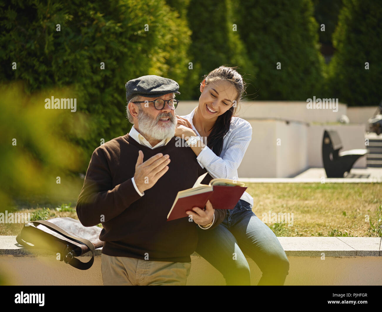 Aider quelqu'un que vous aimez. Portrait of young smiling girl embracing grand-père avec réserve contre city park. communauté et de vie de la famille concept Banque D'Images