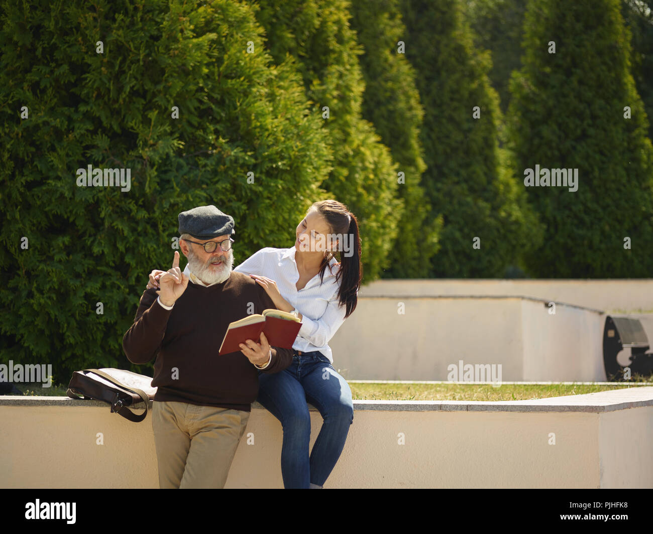 Aider quelqu'un que vous aimez. Portrait of young smiling girl embracing grand-père avec réserve contre city park. communauté et de vie de la famille concept Banque D'Images