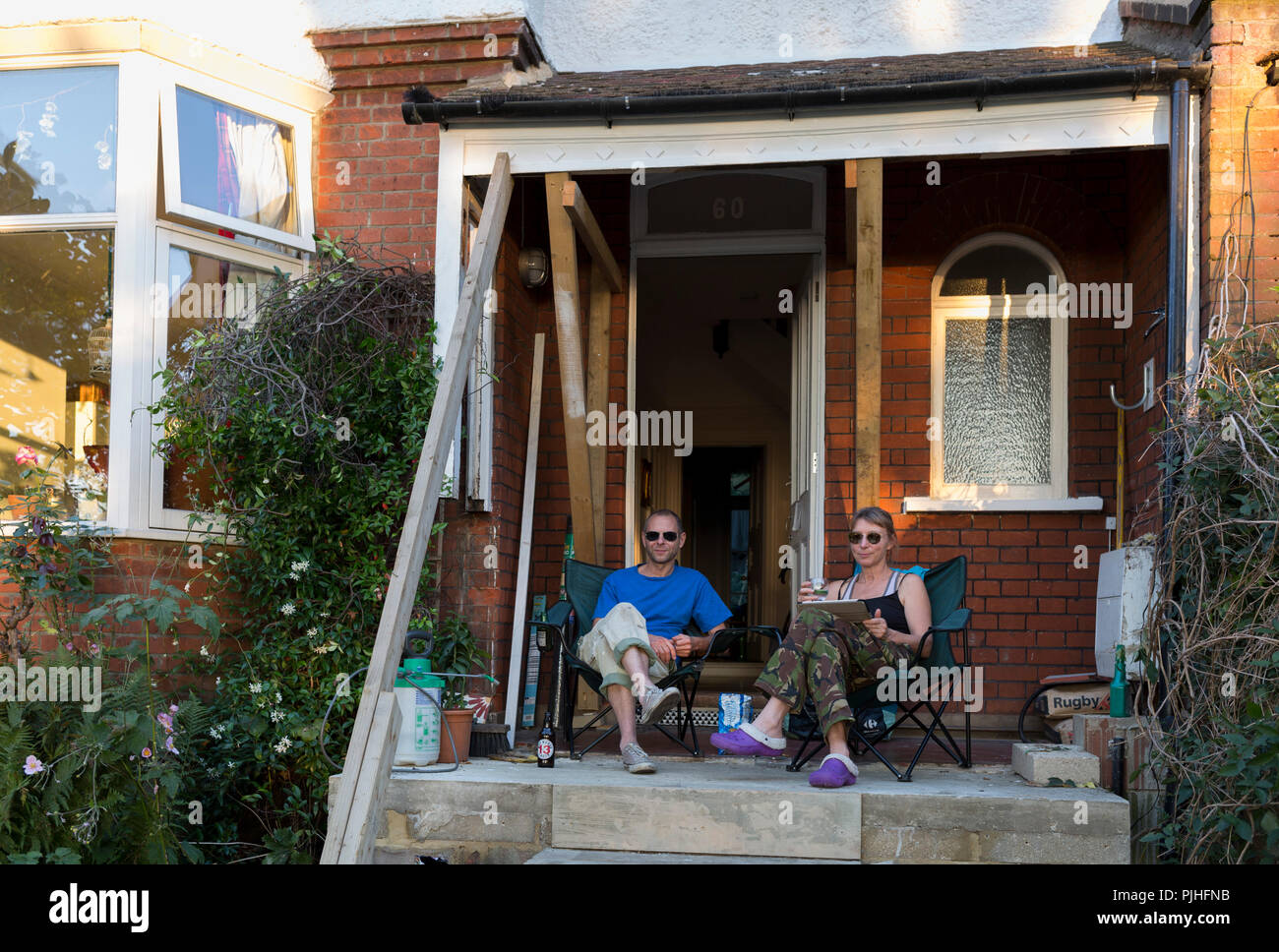 Un couple s'asseoir avec un verre le soir sur leur maison édouardienne porche lors d'une re-construction du projet, le 1er septembre 2018, dans le sud de Londres en Angleterre. Banque D'Images