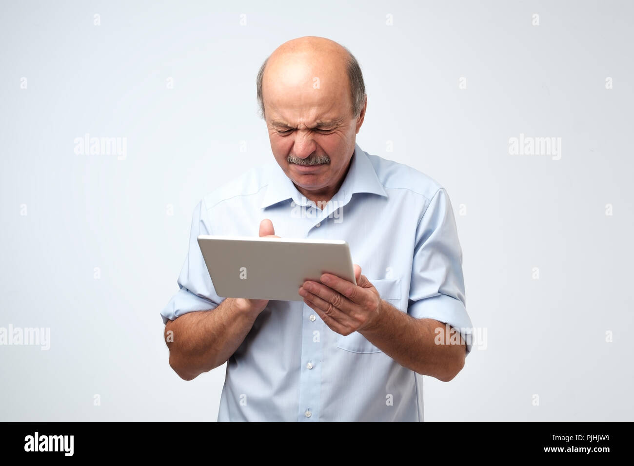 Young man est dégoûté par ce qu'il voit sur une tablette. Il est à la vidéo dans Internet et est vraiment choqué Banque D'Images