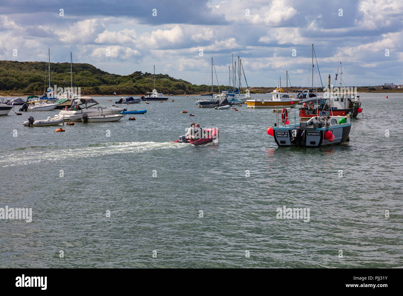 Deux hommes d'un petit canot pneumatique à moteur à travers les amarres à Hengistbury Head, Dorset, UK Banque D'Images