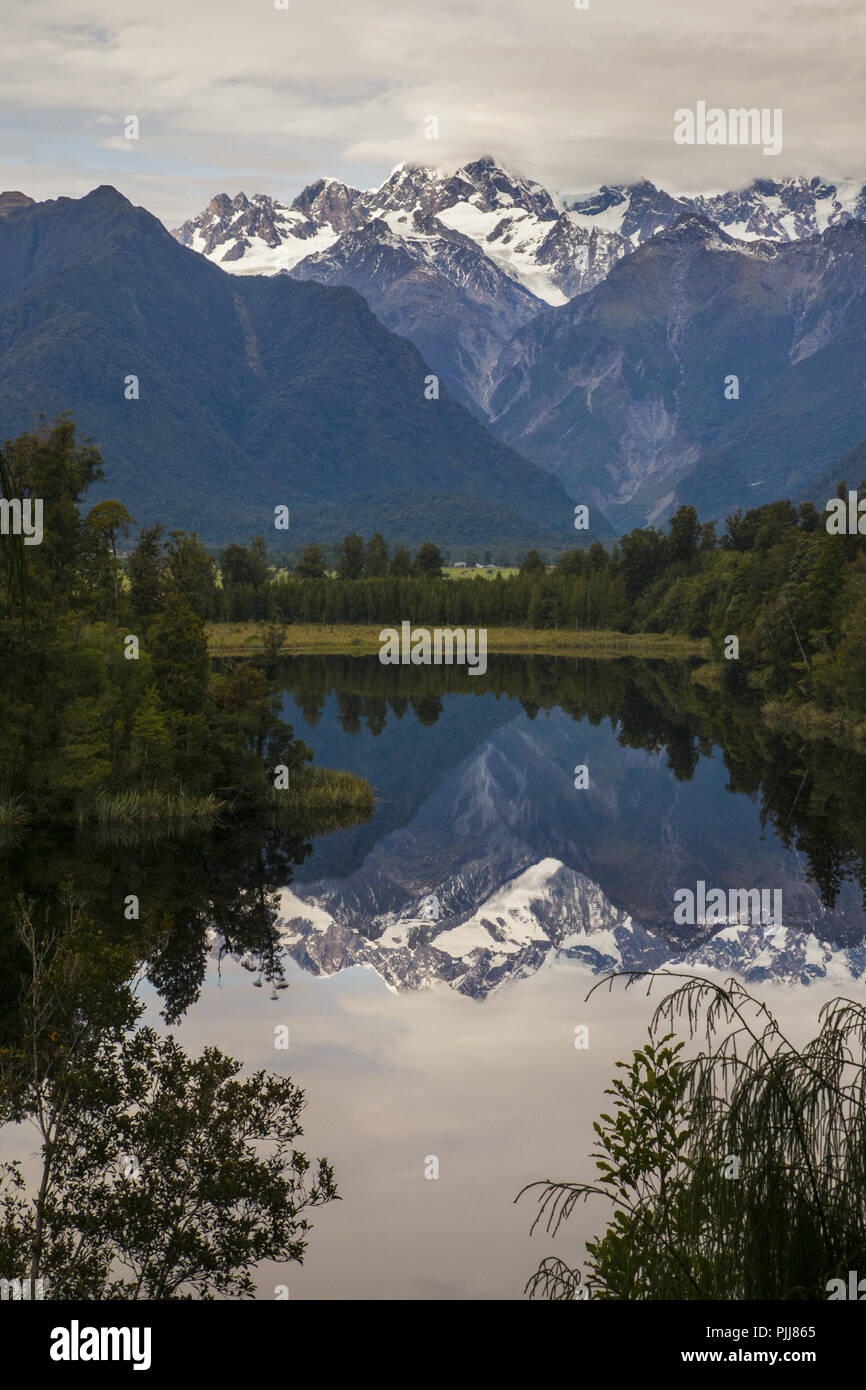 Nature étonnante vue de calme Mountain Lake Matheson, réflexion miroir reflétant l'eau sommets de montagnes des Alpes du Sud avec Fox Glacier en voie de disparition Banque D'Images