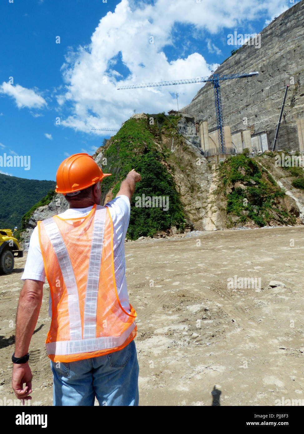 Signalisation d'un ingénieur d'une grue lors d'une visite à un site de construction verticale portant casque de sécurité Banque D'Images