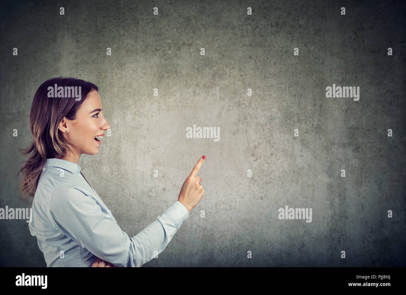 Vue latérale du doigt de maintien femme excitée par avoir idée lumineuse sur fond gris Banque D'Images