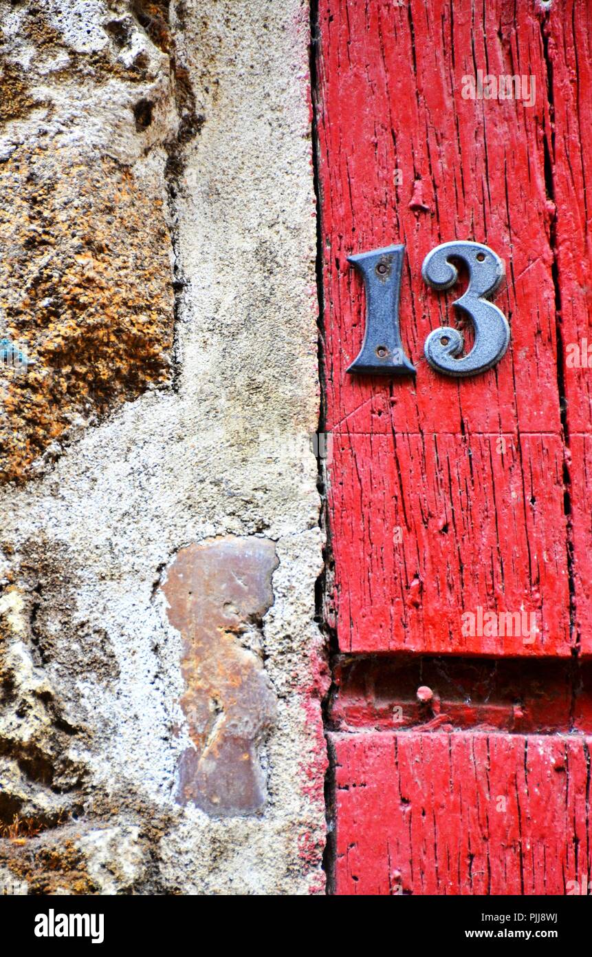 Chambre numéro 13 sur un mur rustique, deux vieux, Rusty metal numéros sur bois peint rouge Banque D'Images