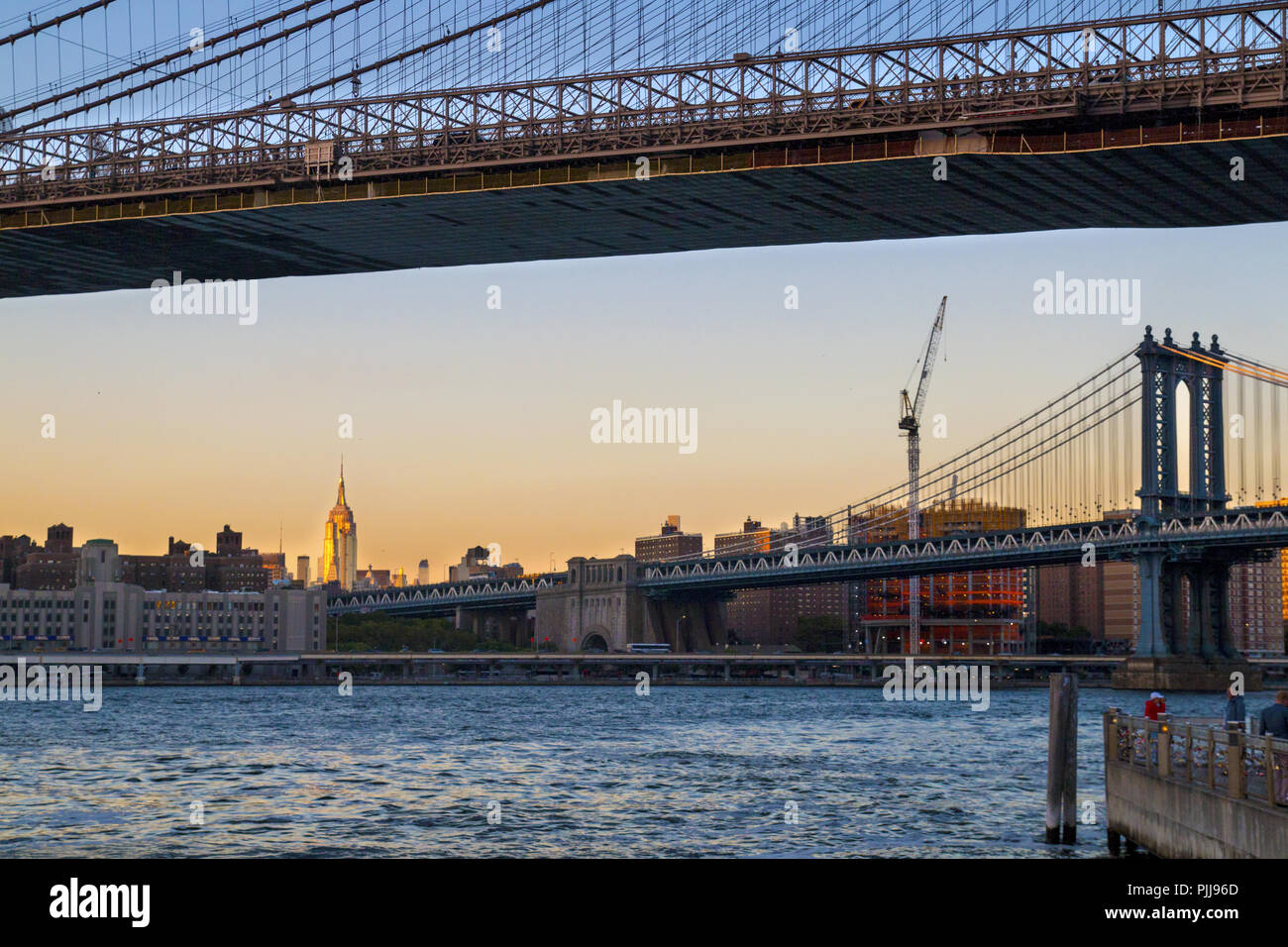 Les ponts de la ville de New York, Manhattan vue du pont Brooklyn Bridge et en face, l'Empire State Building à pied, coucher de soleil lumière, NY USA Banque D'Images