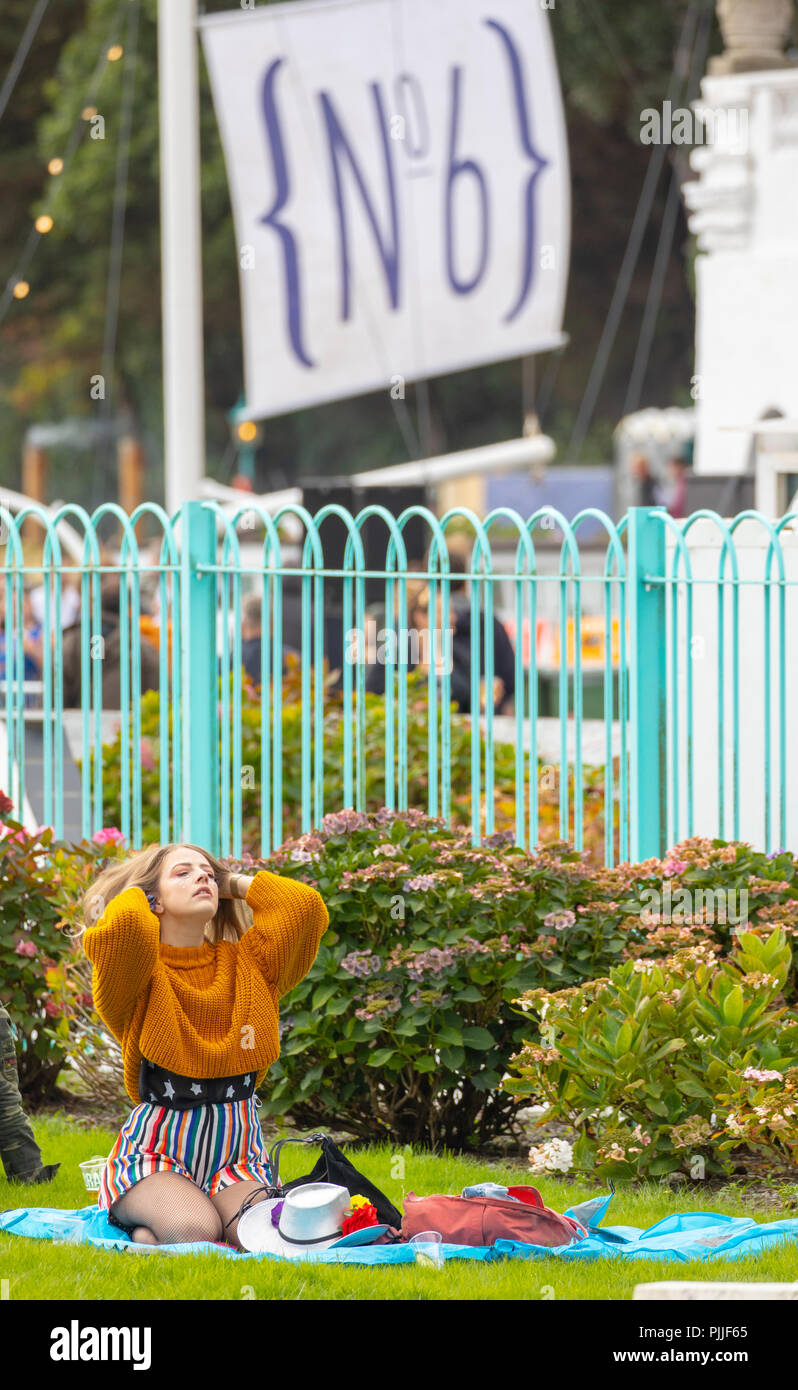 Portmeirion, le Nord du Pays de Galles le 7 septembre 2018 : Festival no 6 est multi-award-winning de la musique, festival des arts et de la culture que tout se déroule dans le magnifique cadre de conte de fées de Portmeirion, au nord du Pays de Galles, l'accueil de l'émission de télévision culte le prisonnier. Un habitué du festival Festival de détente à numéro 6 en jouant avec ses cheveux alors qu'assis sur un tapis de pique-nique, Portmeirion, au Pays de Galles Banque D'Images