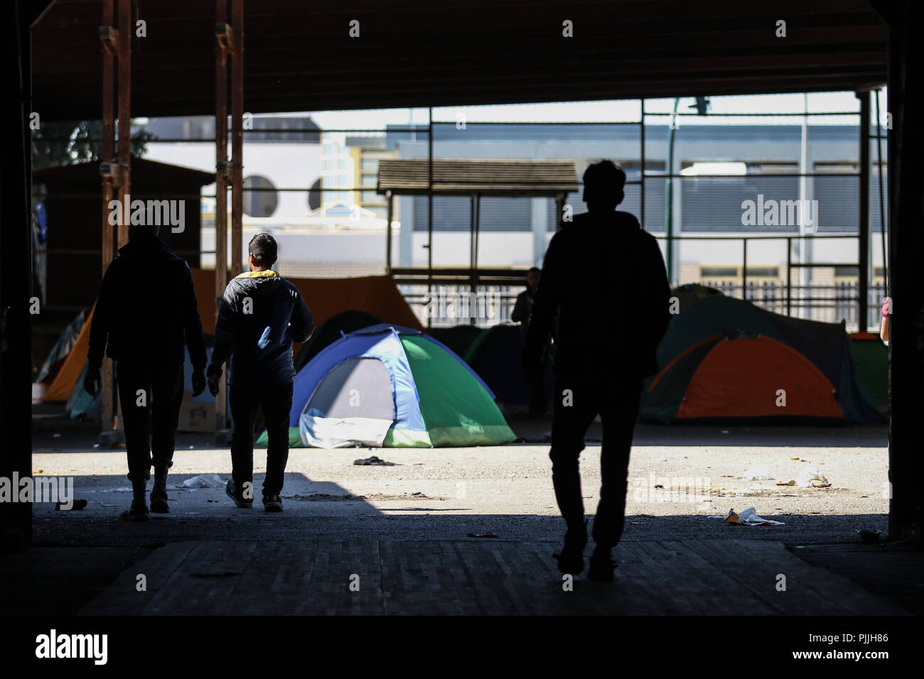 Patra, Achaïe, Grèce. Mar 29, 2018. Silhouettes de réfugiés marche à côté de leurs tentes dans une cour abandonnés.Les Migrants et les réfugiés à trouver refuge dans un camp de fortune qu'ils ont pris à un ancien marchand à côté de port de Patras. Le port de la ville est devenue un important point de départ pour les sans-papiers et les réfugiés qui tentent de se rendre en Italie et de là à d'autres pays en Europe. Essayez les migrants pour accéder au port et se cachent dans les camions en attente d'être envoyé à l'Italie par ferry. Menelaos Crédit : Michalatos SOPA/Images/ZUMA/Alamy Fil Live News Banque D'Images