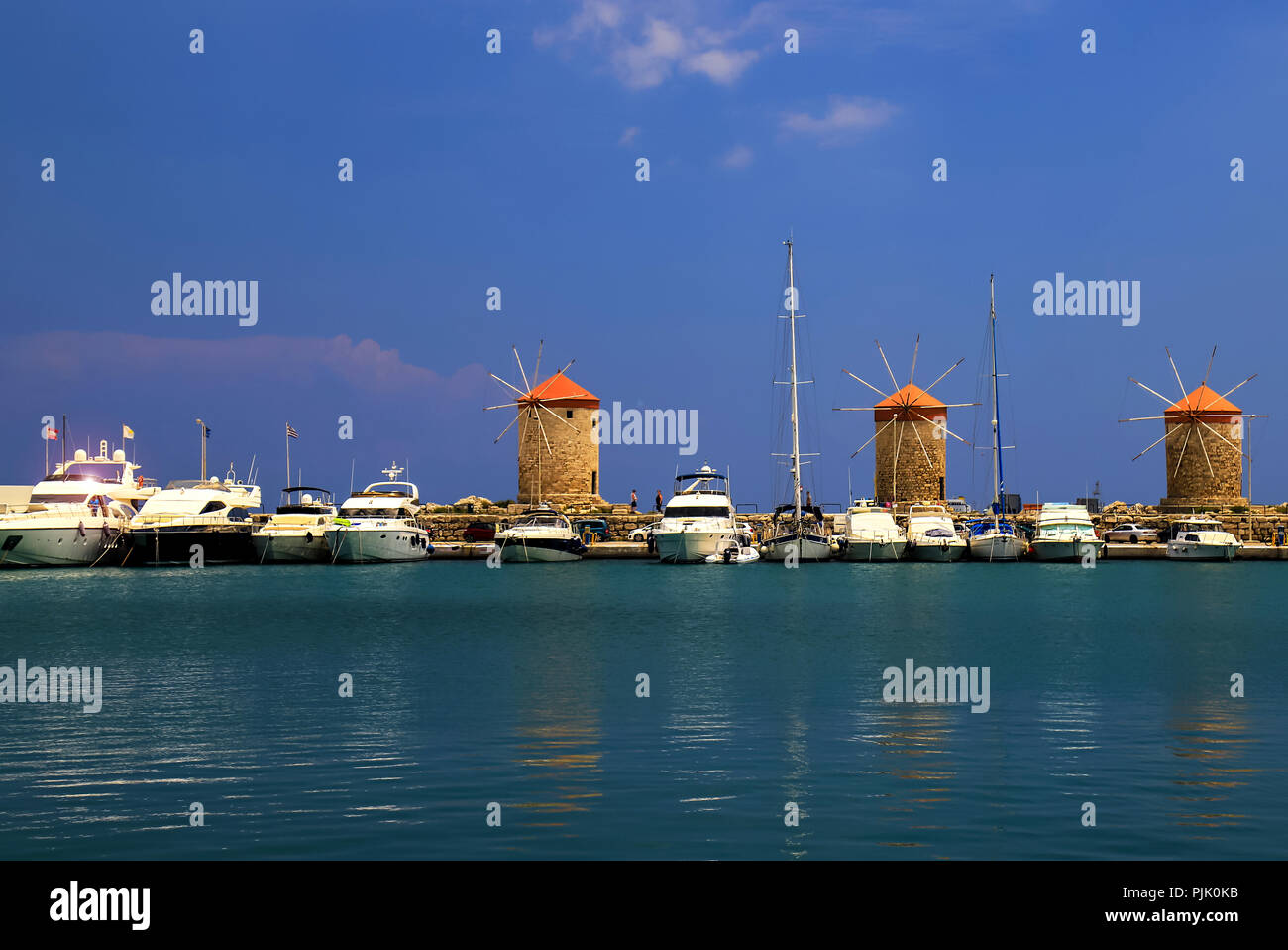 Jaune et orange vieux moulins à vent dans le port, les yachts et les blancs, de la mer turquoise. Rhodes, Grèce - un lieu pour des excursions, voyages Banque D'Images