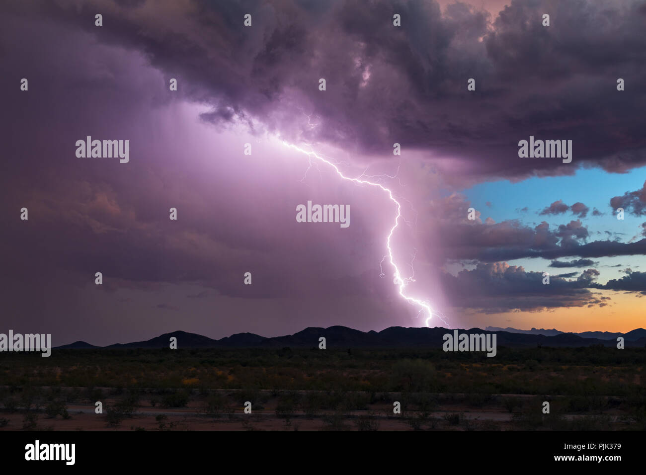 Une frappe éclair lumineuse et un ciel de coucher de soleil lors d'une tempête de mousson dans les montagnes du désert près de Gila Bend, Arizona Banque D'Images