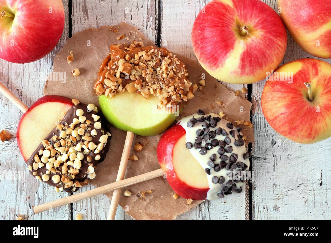 Les pommes d'automne feux ronds avec du chocolat et caramel, au-dessus de bois blanc rustique sur scène Banque D'Images