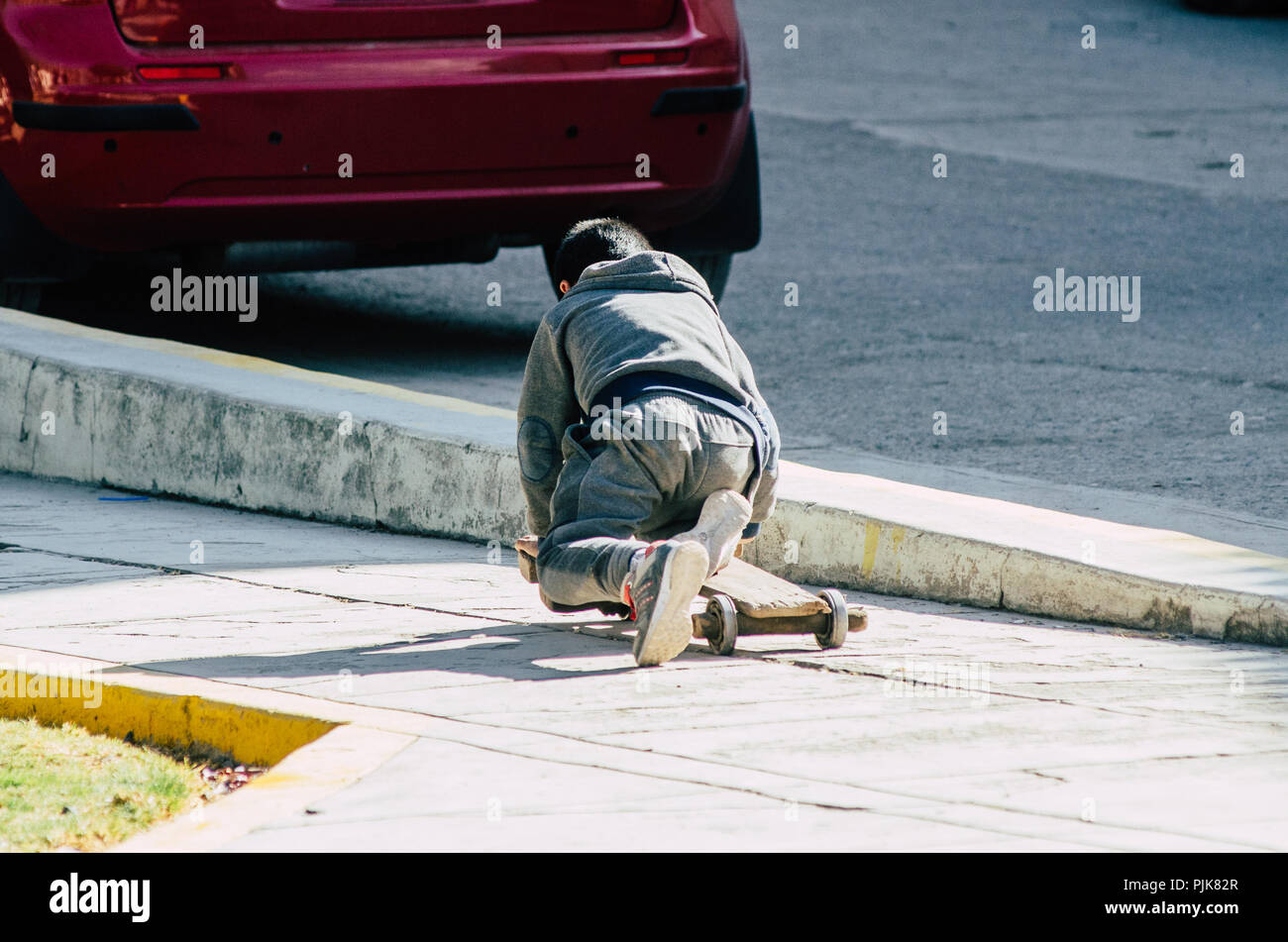 Enfant jouant dans la rue avec un artisan à roulettes sur une journée ensoleillée Banque D'Images