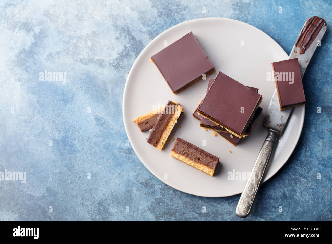 Tranches de chocolat caramel, bars, les millionnaires shortbread sur une plaque gris. Fond bleu. Vue d'en haut Banque D'Images